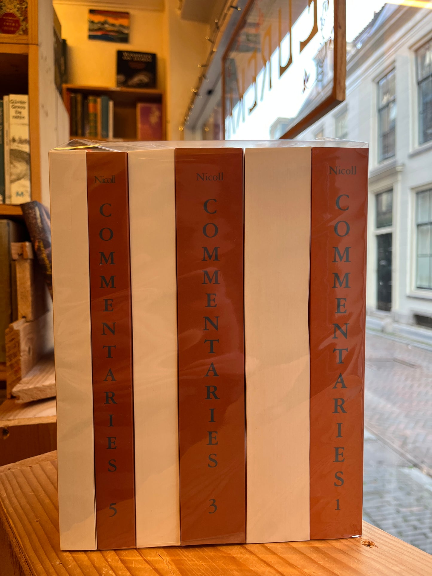 Set of books titled 'Commentaries' on a wooden surface with a blurred indoor background