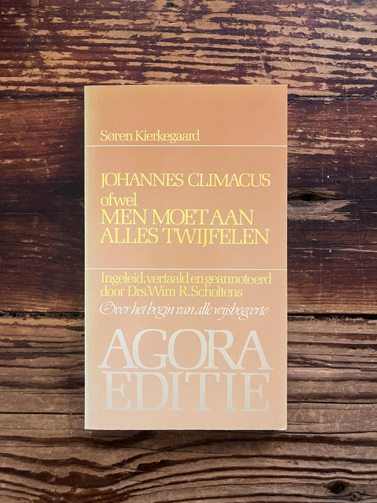 foto van de cover van het boek "men moet aan alles tijwfelen"op houten achtergrond