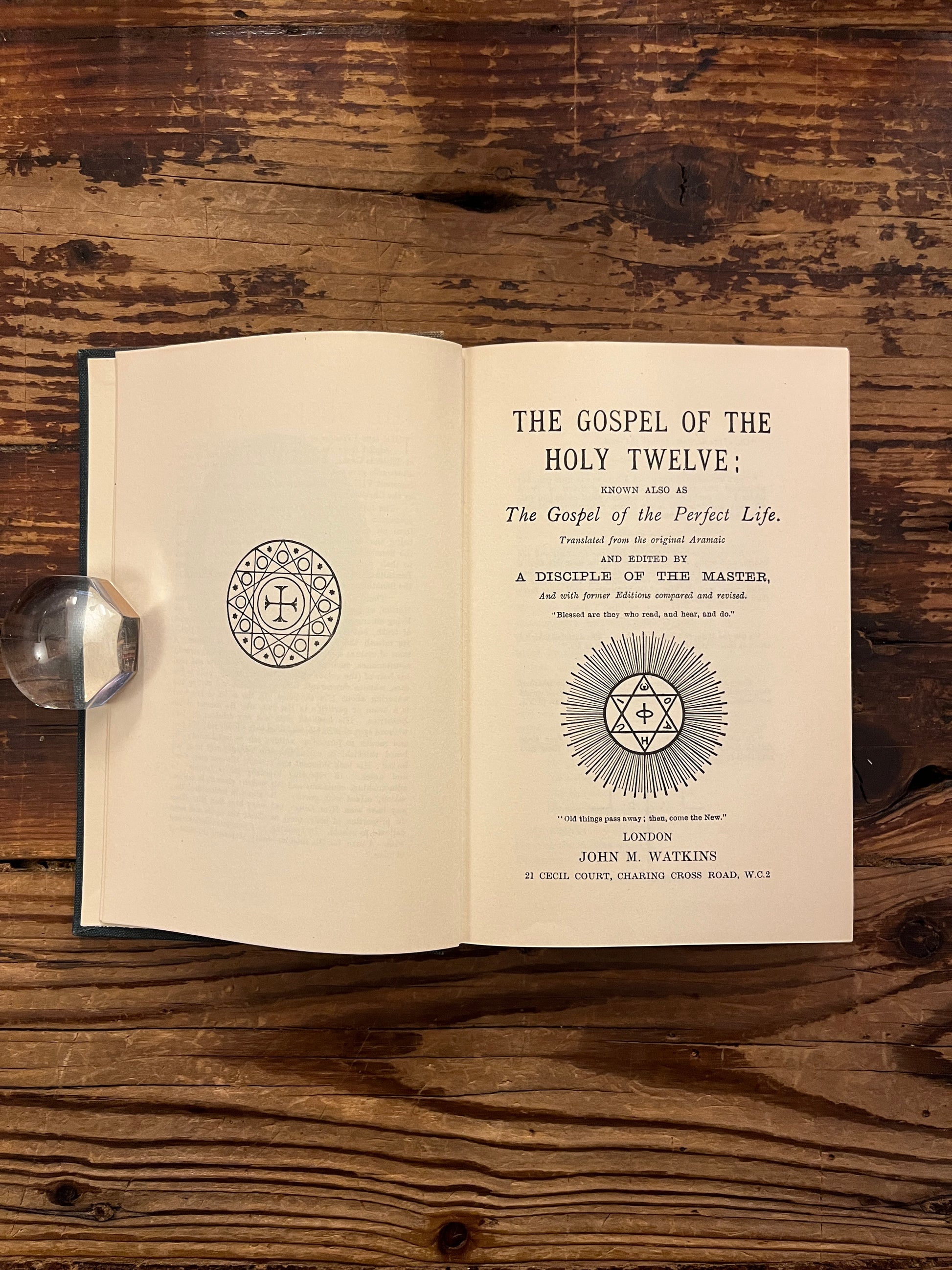 Open book titled 'The Gospel of the Holy Twelve' by J.R. Ouseley on a wooden surface