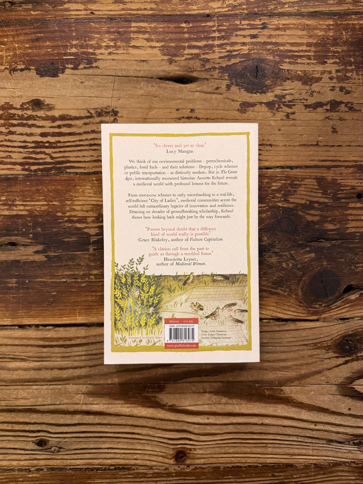 Back cover of the book 'The Green Ages' by Annette Kehnel on a wooden surface