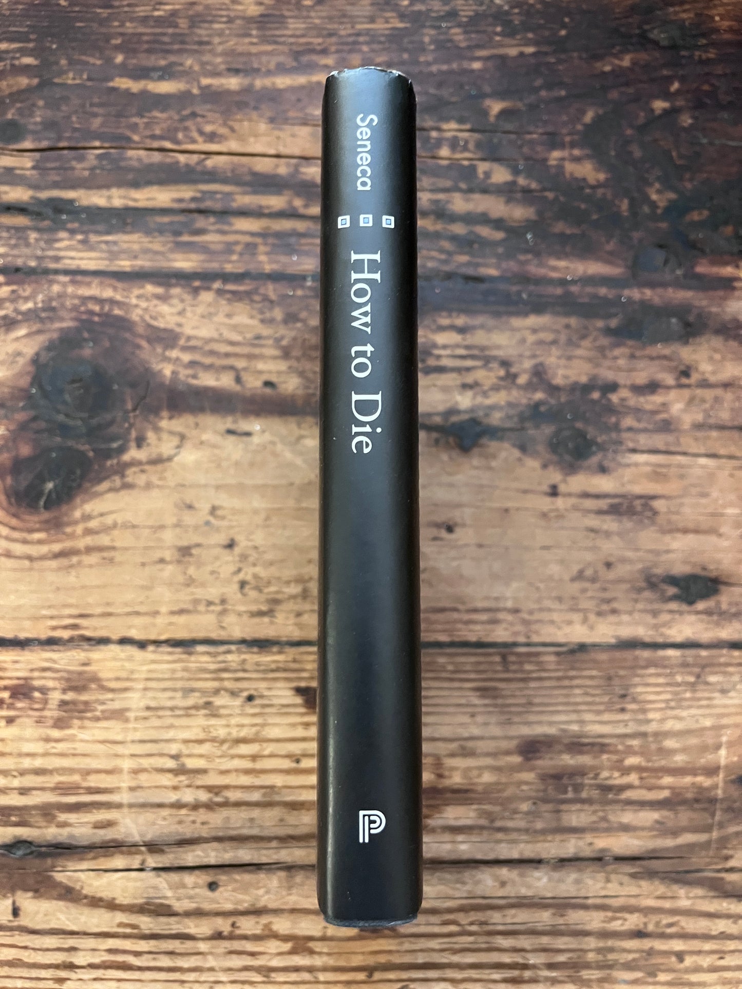 photo of the spine of the book of the book "how to die" on a wooden background