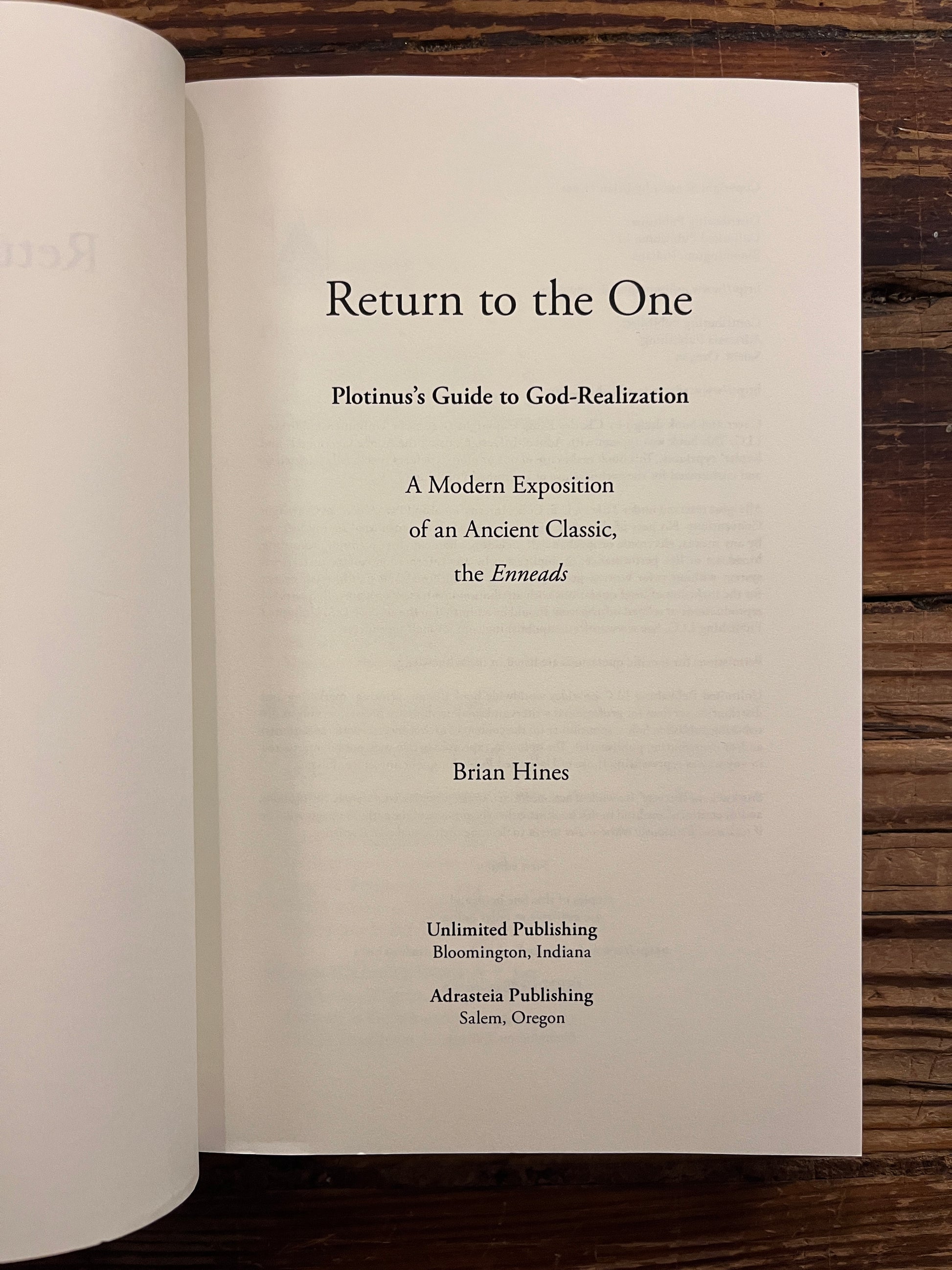 Open book titled 'Return to the One, Plotinus guide to God-Realization' by Brian Hines on a wooden surface