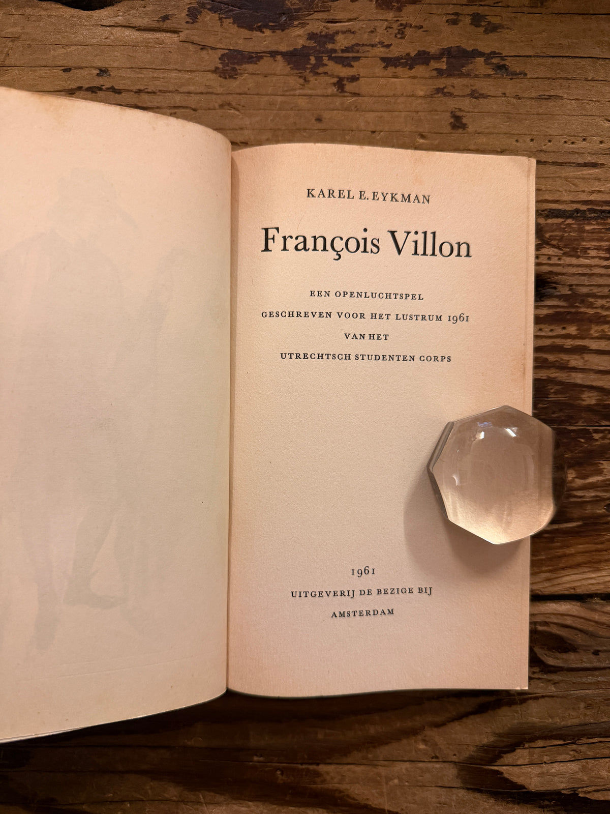 Open boek met de titel 'Francois Villon, openluchtspel, lustrum 1961' door Karel Eykman op een houten achtergrond