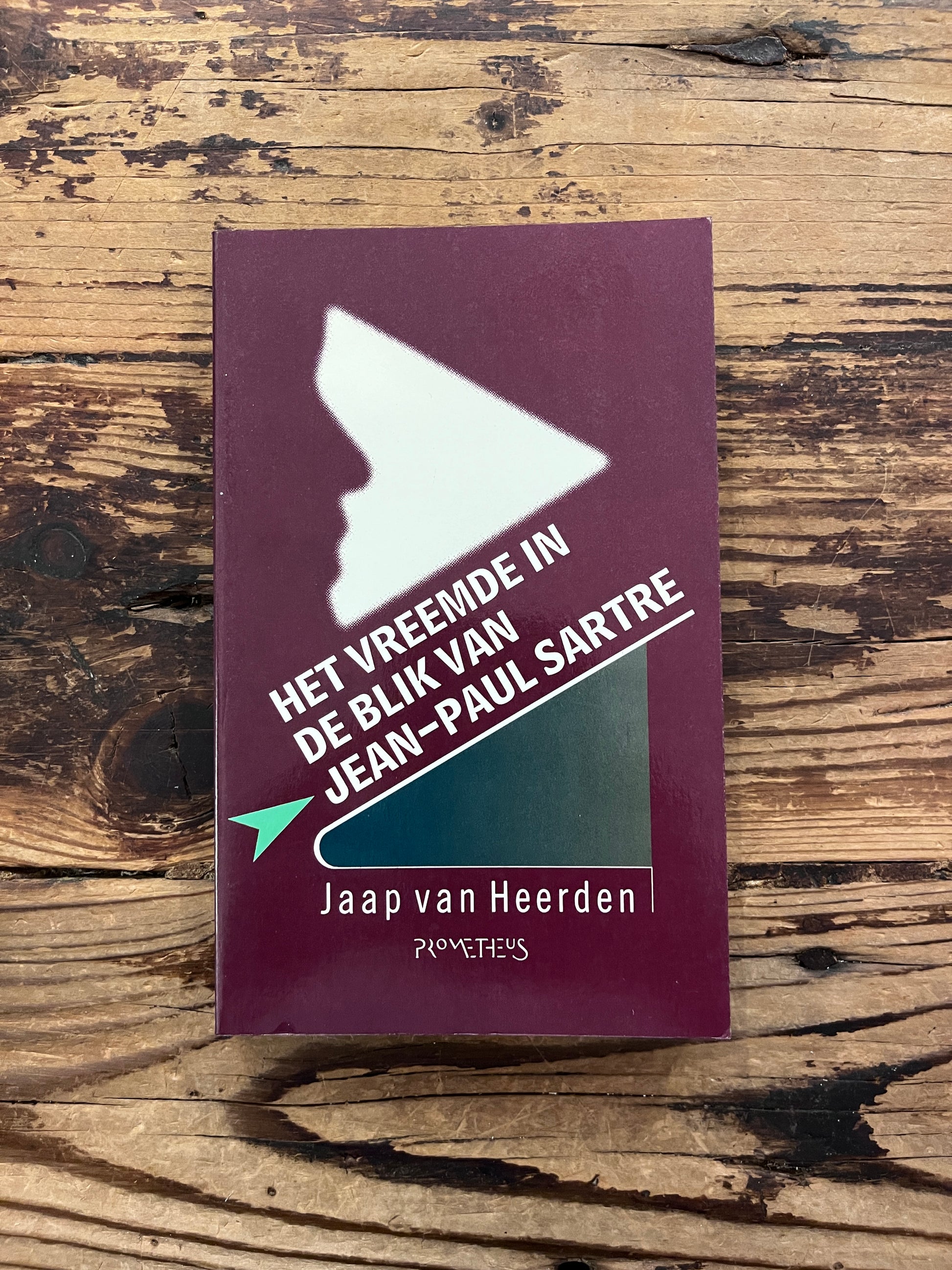 foto van de omslag van het boek "het vreemde in de blik van Jean-Paul Sartre" op houten achtergrond