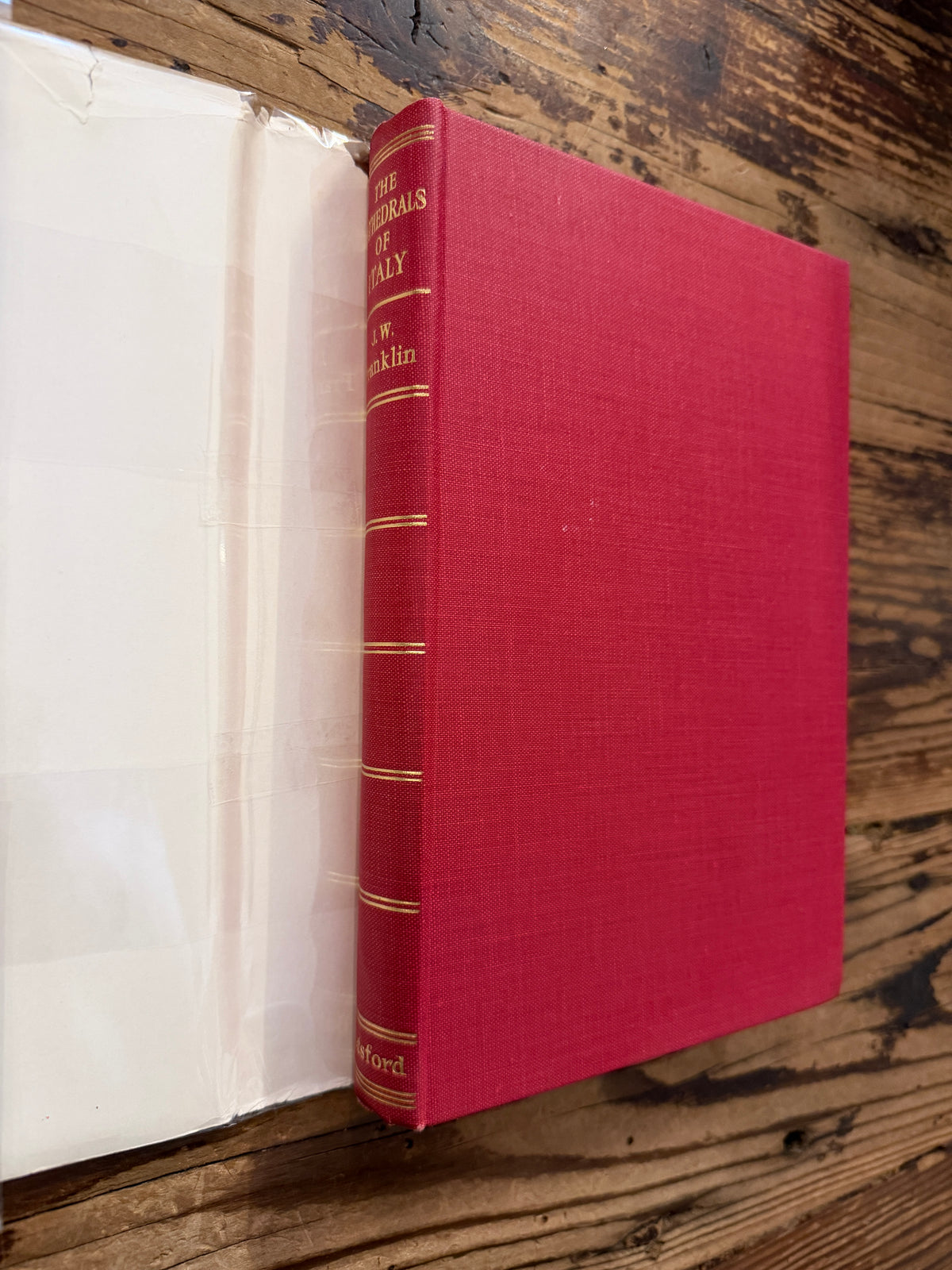 Front cover and spine without dust jacket of a book with the title 'The Cathedrals of Italy' by J.W. Franklin on a wooden surface