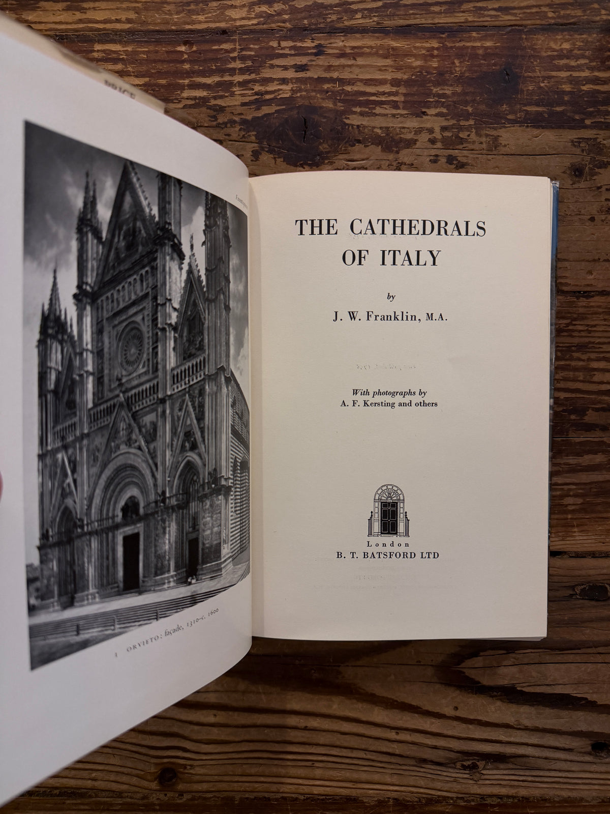 Open book with the title 'The Cathedrals of Italy' by J.W. Franklin on a wooden surface