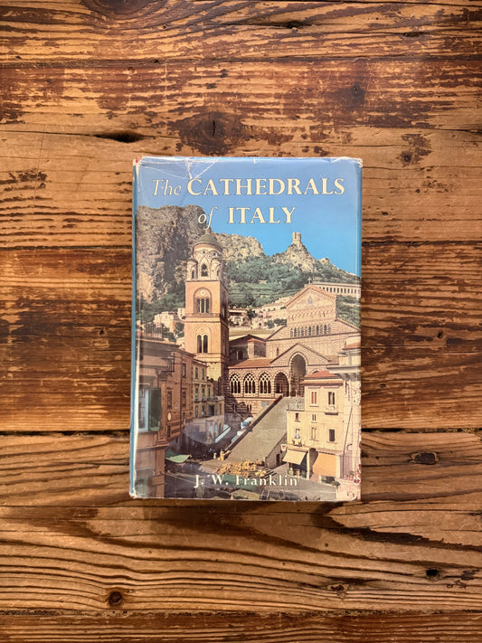 Front cover of a book with the title 'The Cathedrals of Italy' by J.W. Franklin on a wooden surface