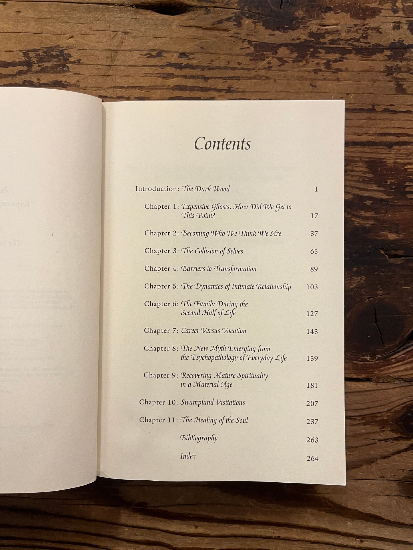 Open book titled 'Finding Meaning in the Second Half of Life' by James Hollis on a wooden surface