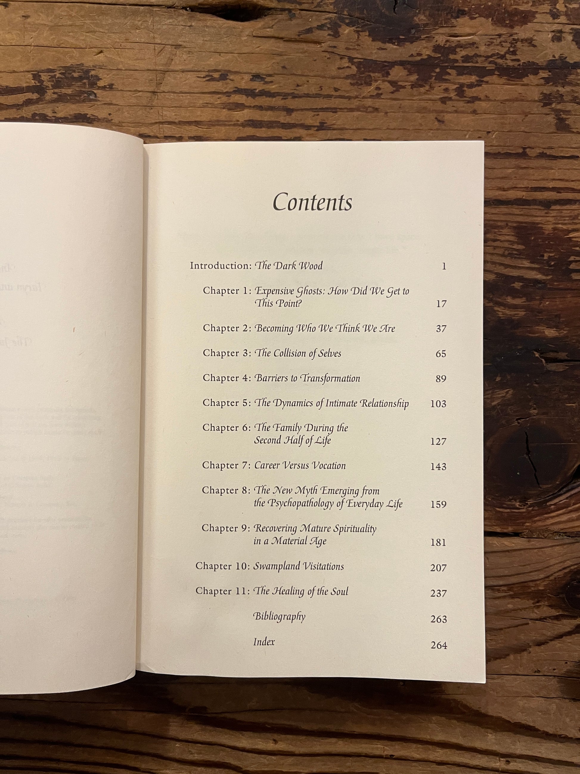 Open book titled 'Finding Meaning in the Second Half of Life' by James Hollis on a wooden surface