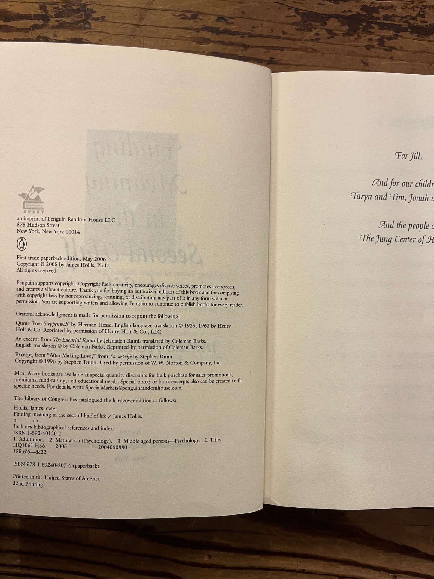 Open book titled 'Finding Meaning in the Second Half of Life' by James Hollis on a wooden surface