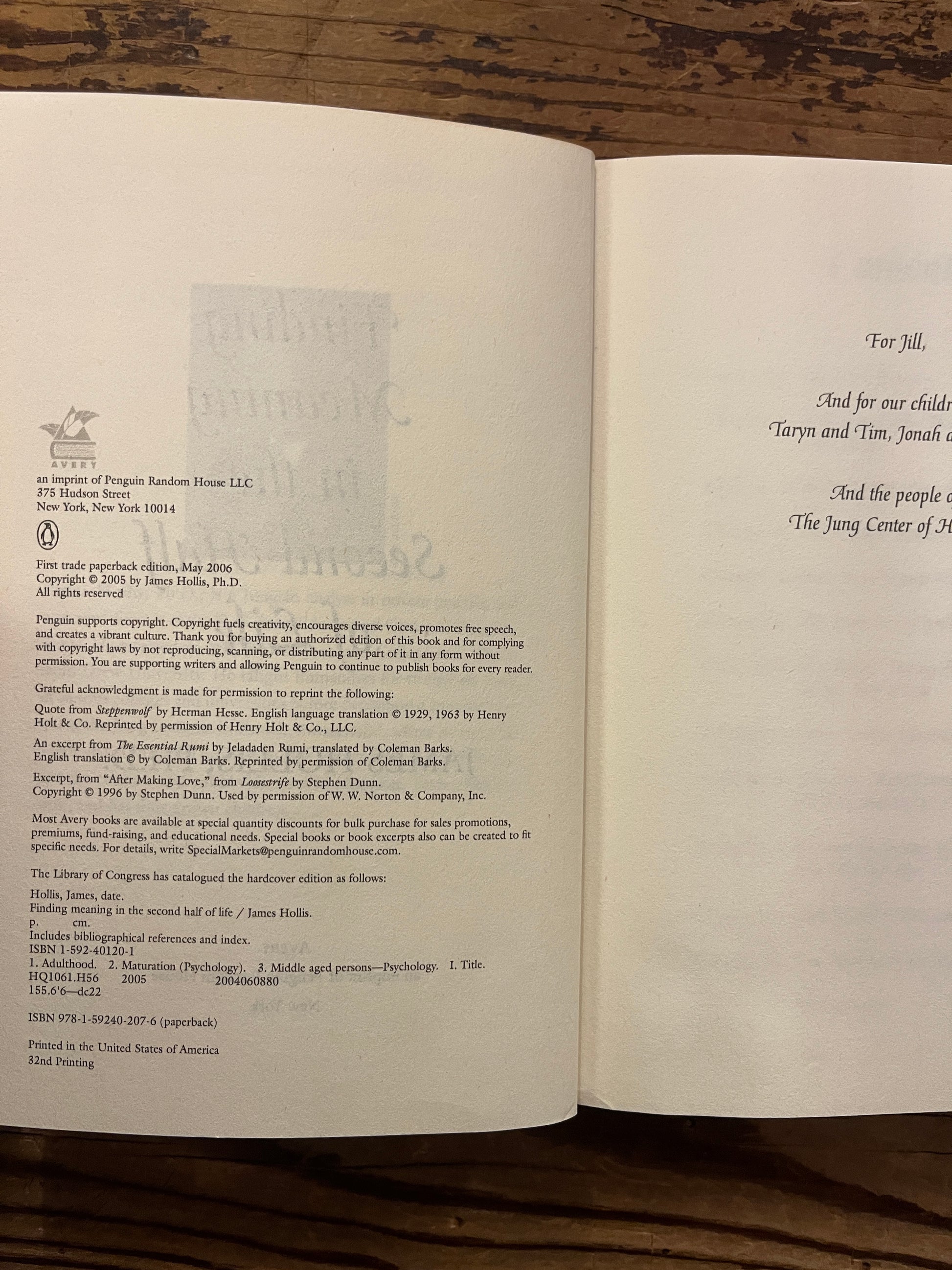 Open book titled 'Finding Meaning in the Second Half of Life' by James Hollis on a wooden surface