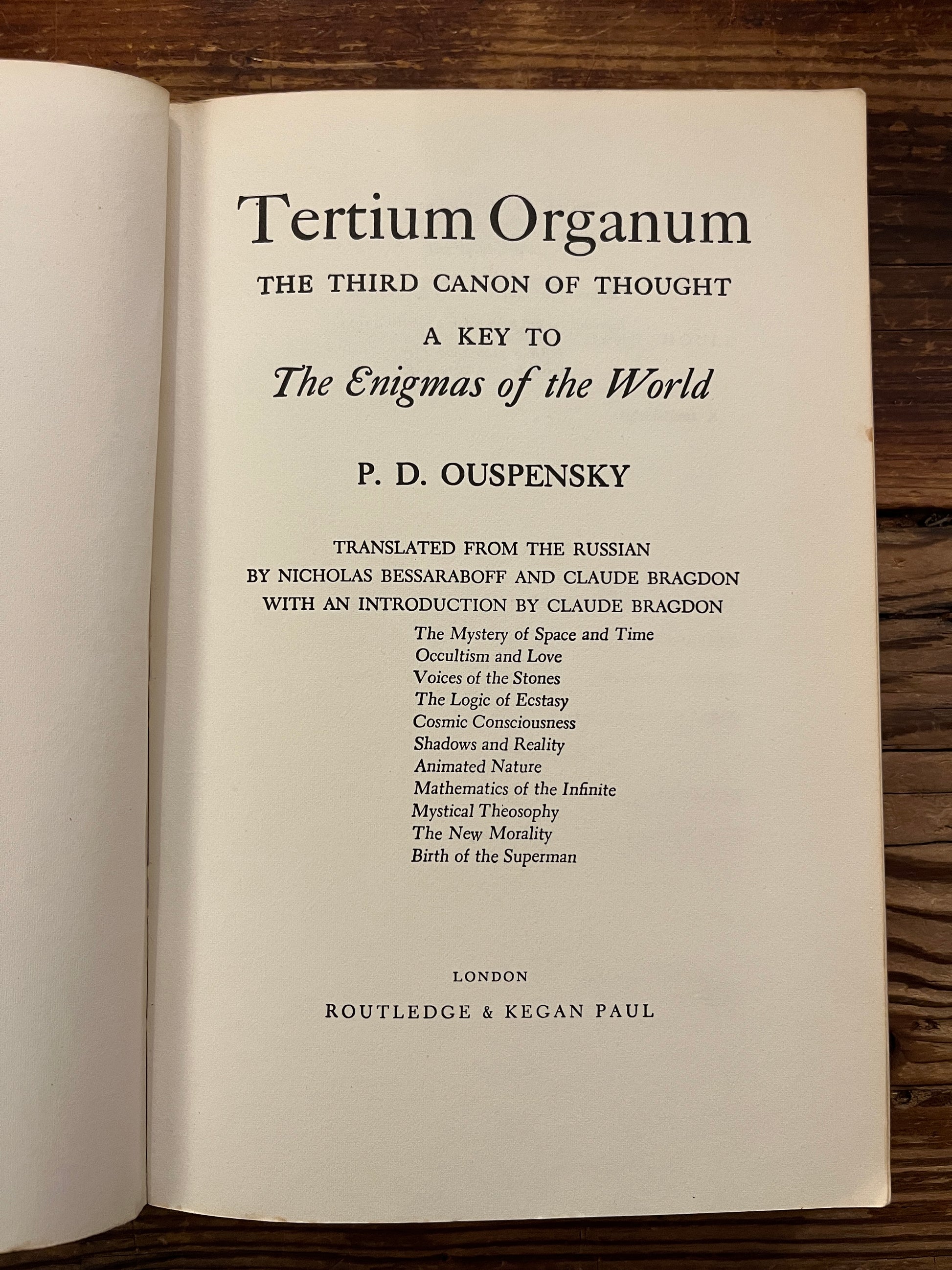 Open book titled 'Tertium Organum' by P.D. Ouspensky on a wooden surface