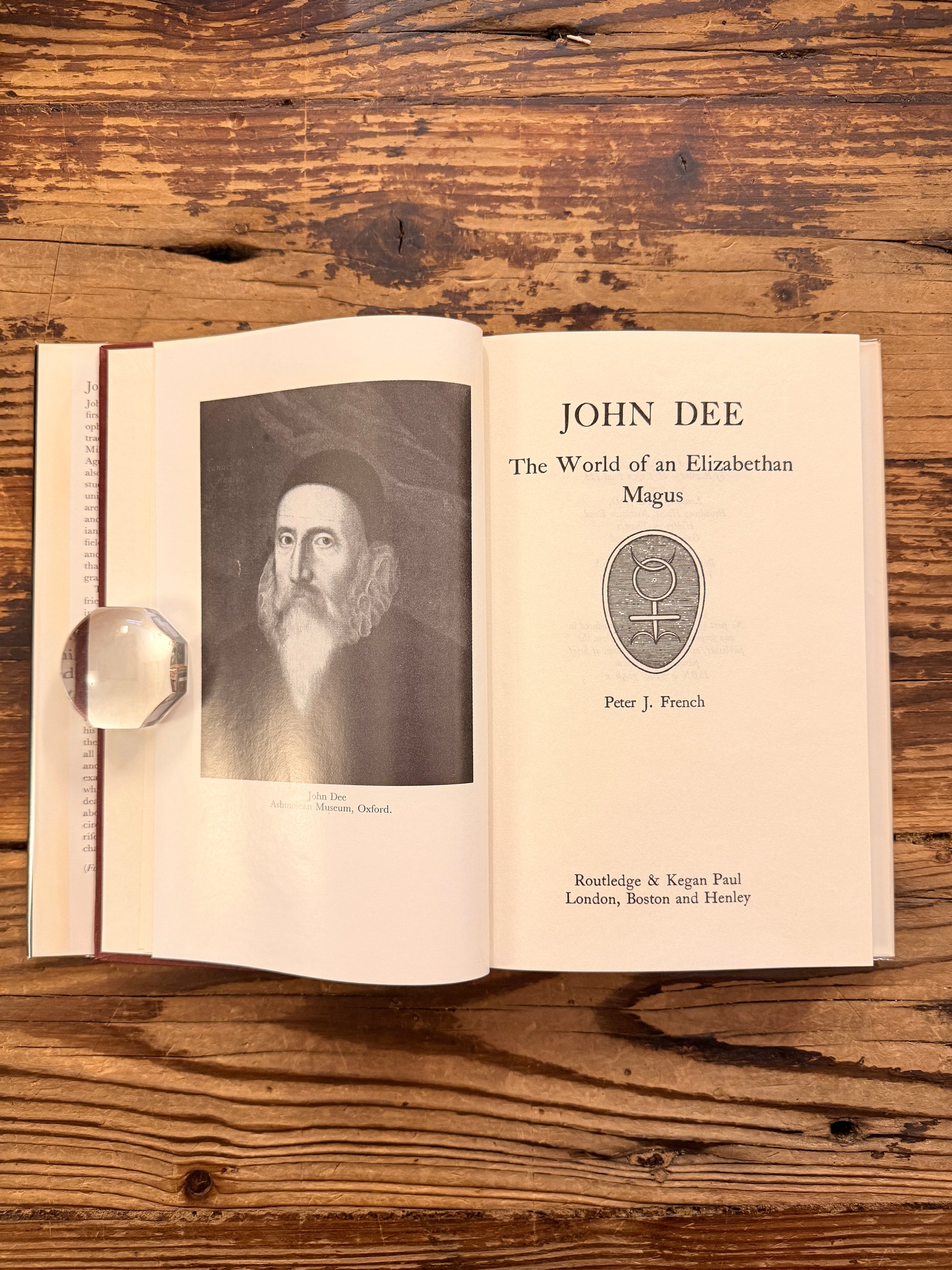 Open book titled 'John Dee: The World of an Elizabethan Magus' by Peter J. French on a wooden surface