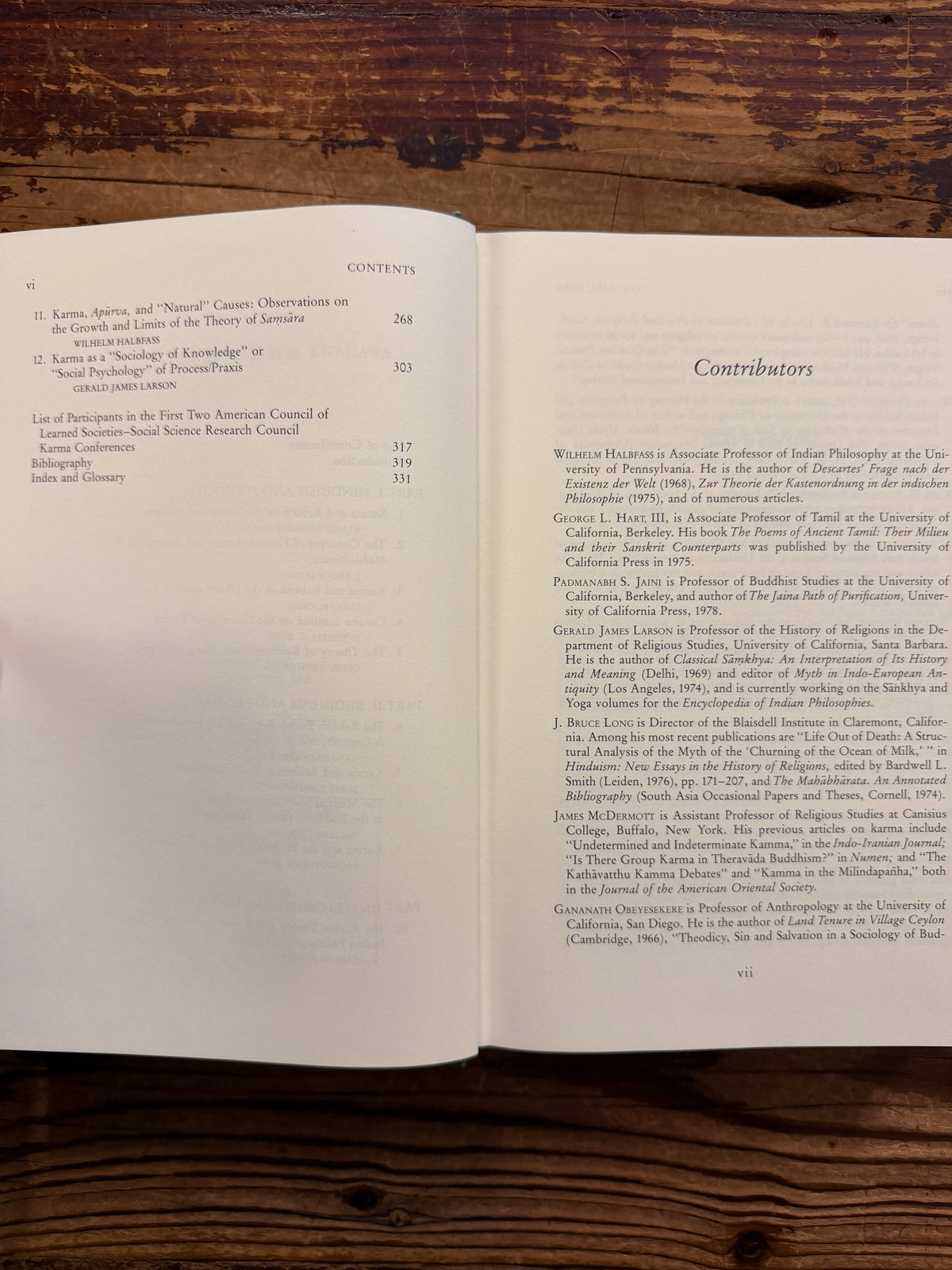 Open book titled 'Karma and Rebirth in Classical Indian Traditions' edited by Wendy Doniger O'Flaherty, on a wooden surface