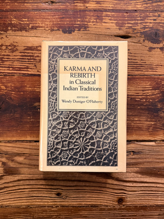 Front cover of a book titled 'Karma and Rebirth in Classical Indian Traditions' edited by Wendy Doniger O'Flaherty, on a wooden surface