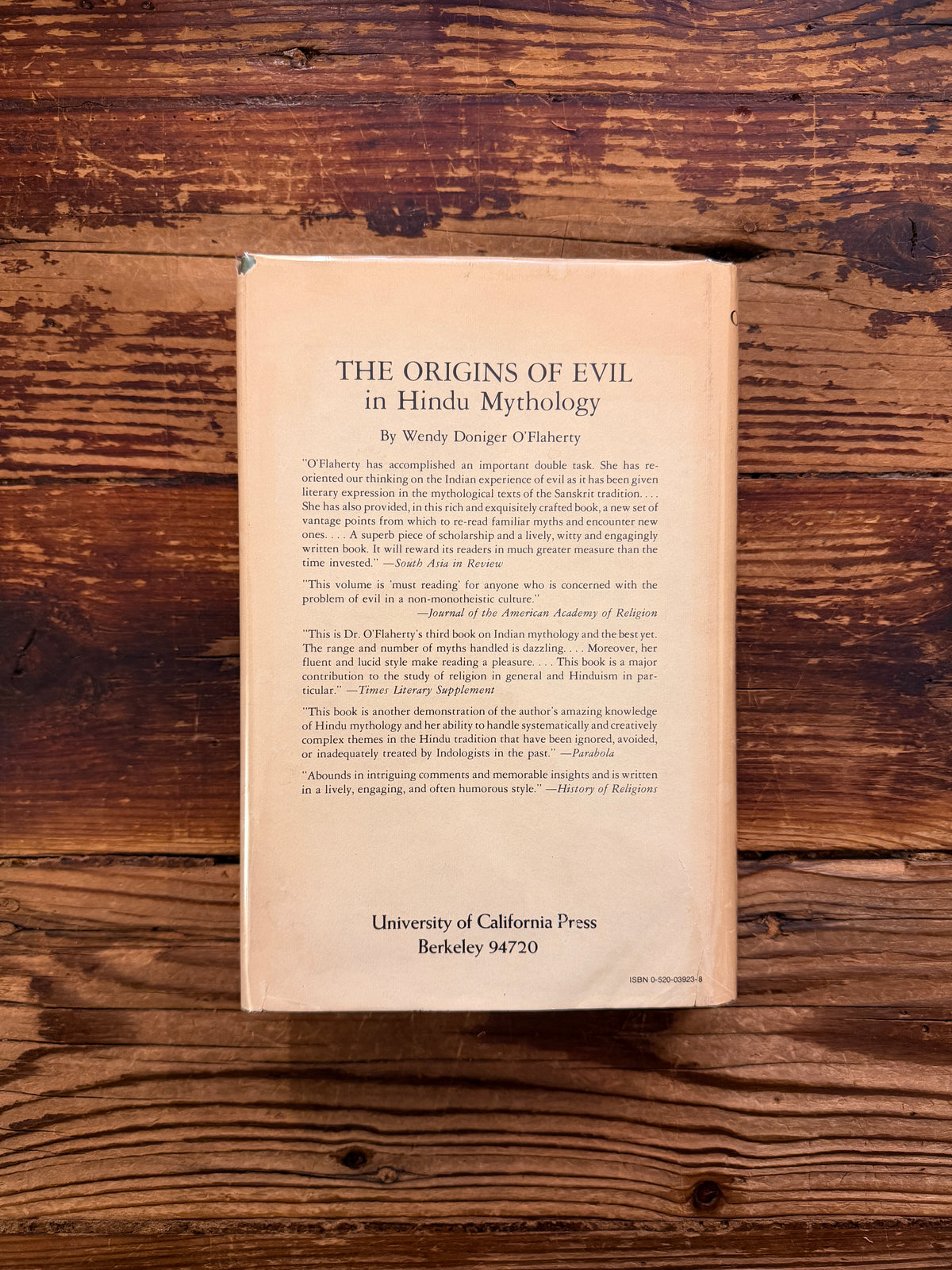 Back cover of a book titled 'Karma and Rebirth in Classical Indian Traditions' edited by Wendy Doniger O'Flaherty, on a wooden surface