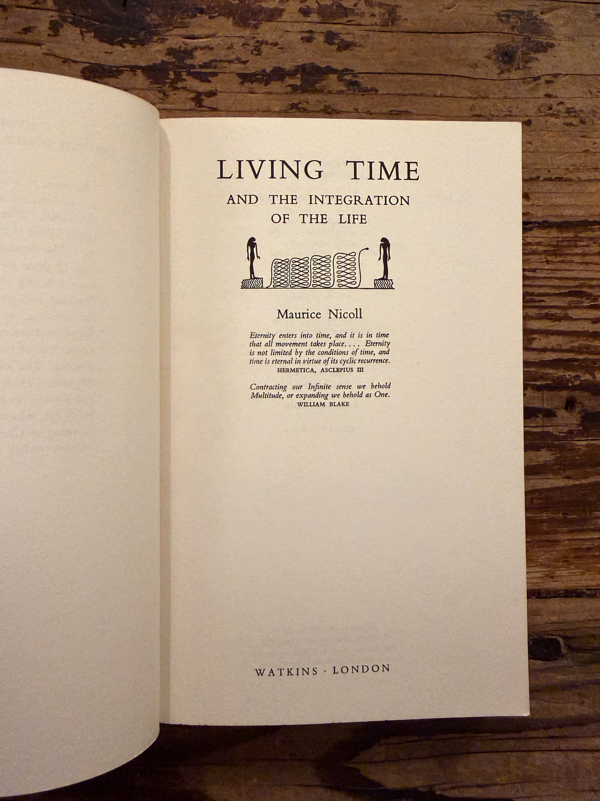 First page of a book with the title 'Living Time and the Integration of the Life' by Maurice Nicoll, a 1976 Watkins Edition lying on a wooden surface 