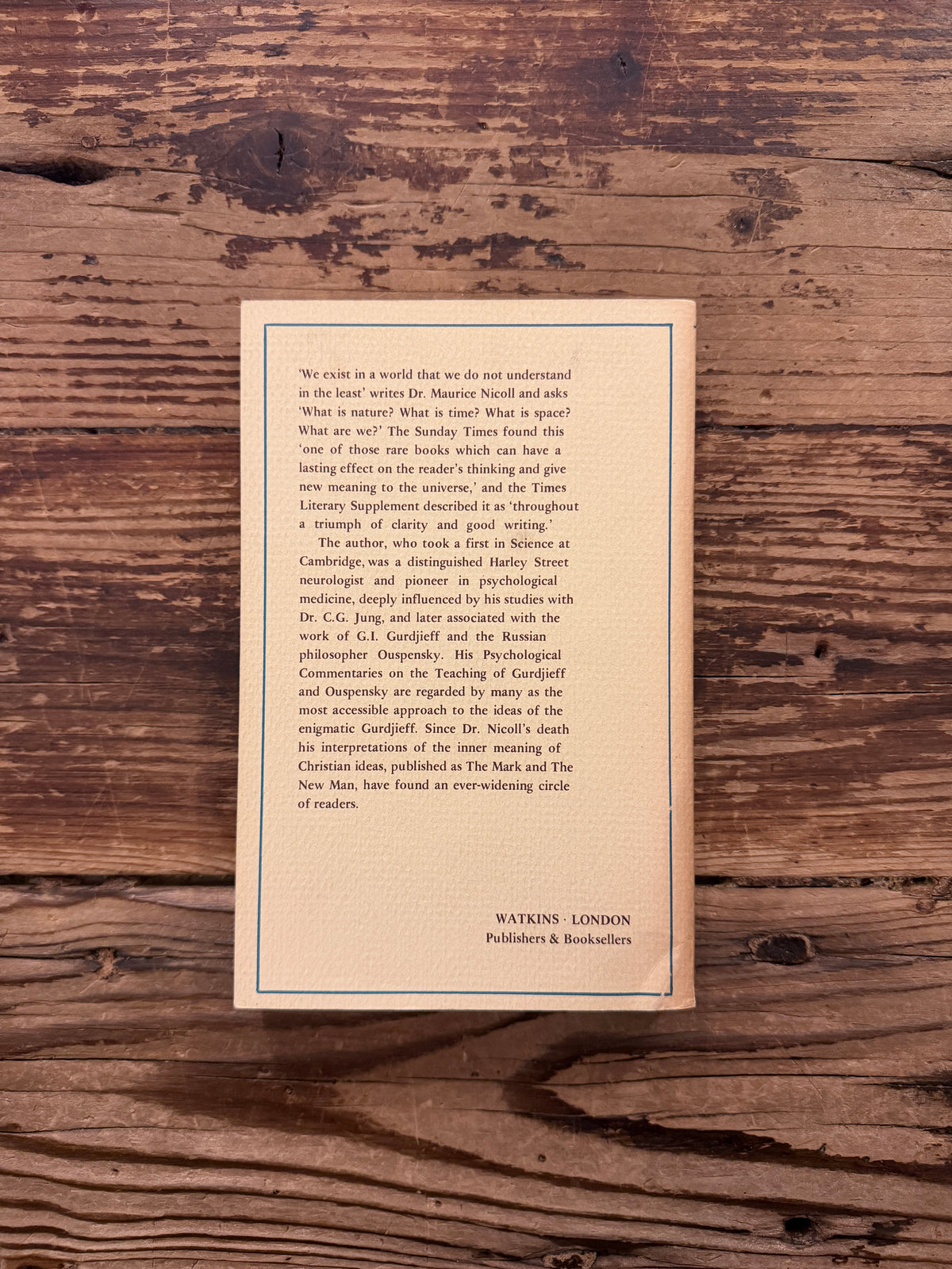 Back cover of a book with the title 'Living Time and the Integration of the Life' by Maurice Nicoll, a 1976 Watkins Edition lying on a wooden surface 
