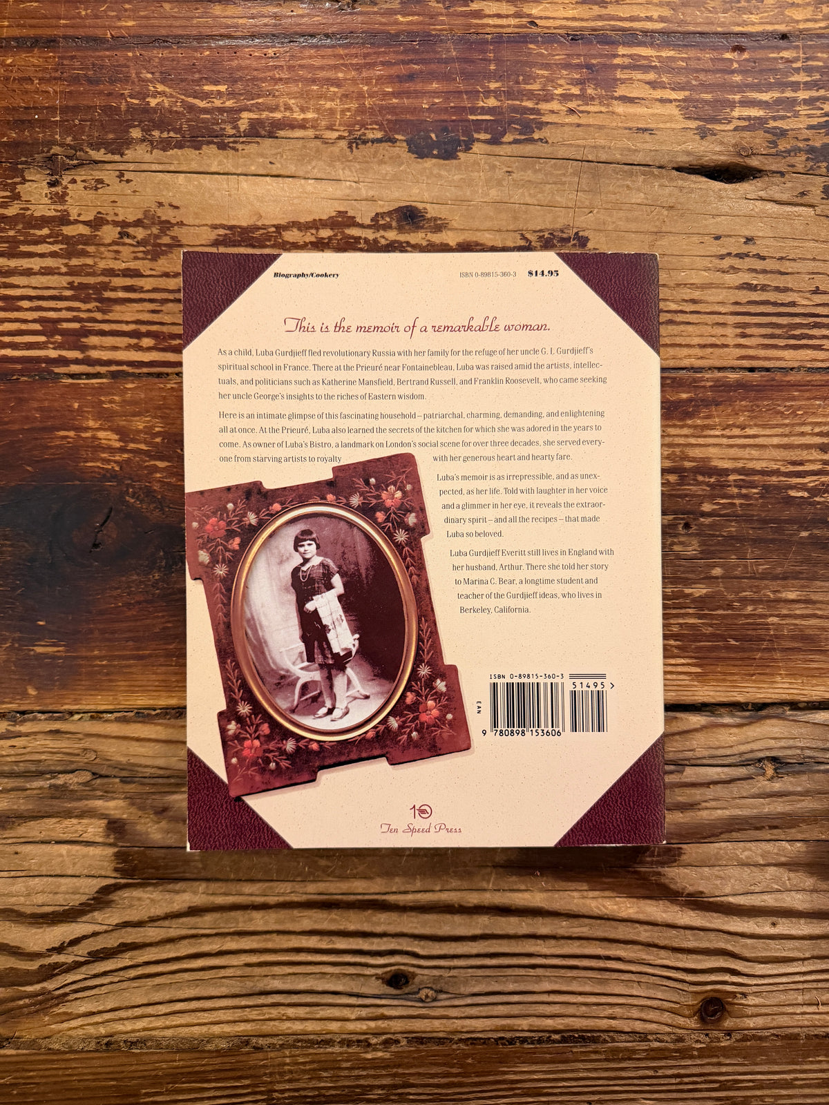 Back cover of a book titled 'Luba Gurdjieff: A Memoir with Recipes' by Luba Gurdjieff Everitt on a wooden surface 