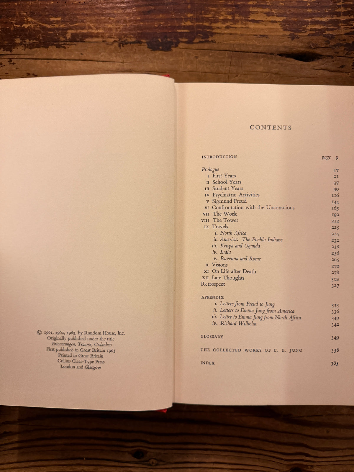 Open book with the titled 'Memories, Dreams, Reflections' by C.G. Jung, 1st English Edition 1963, on a wooden surface 