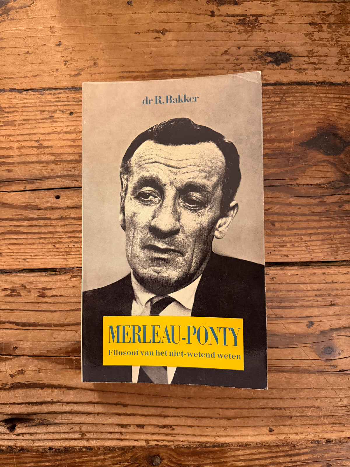 foto van de omslag van het boek "Merleau Ponty filosoof van het niet wetend weten" op houten achtergrond