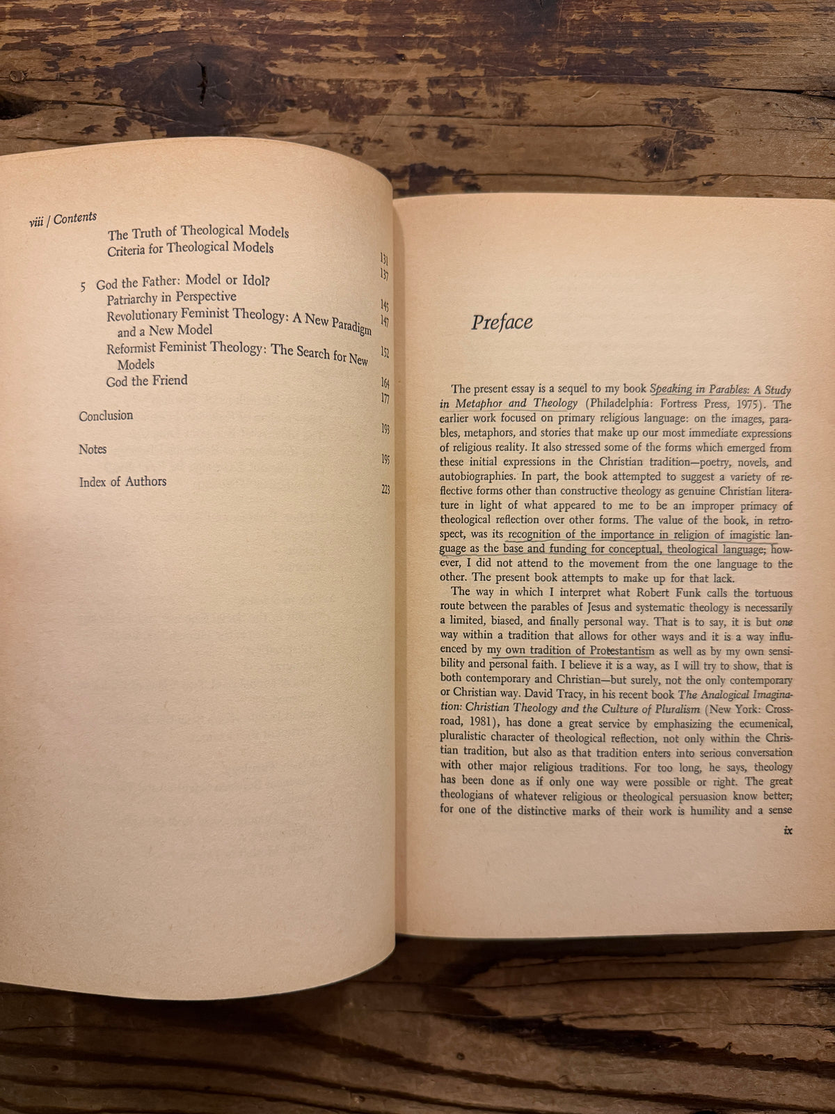 Open book with the title 'Metaphorical Theology, Models of God in Religious Language' by Sallie McFague, exposed on a wooden surface 