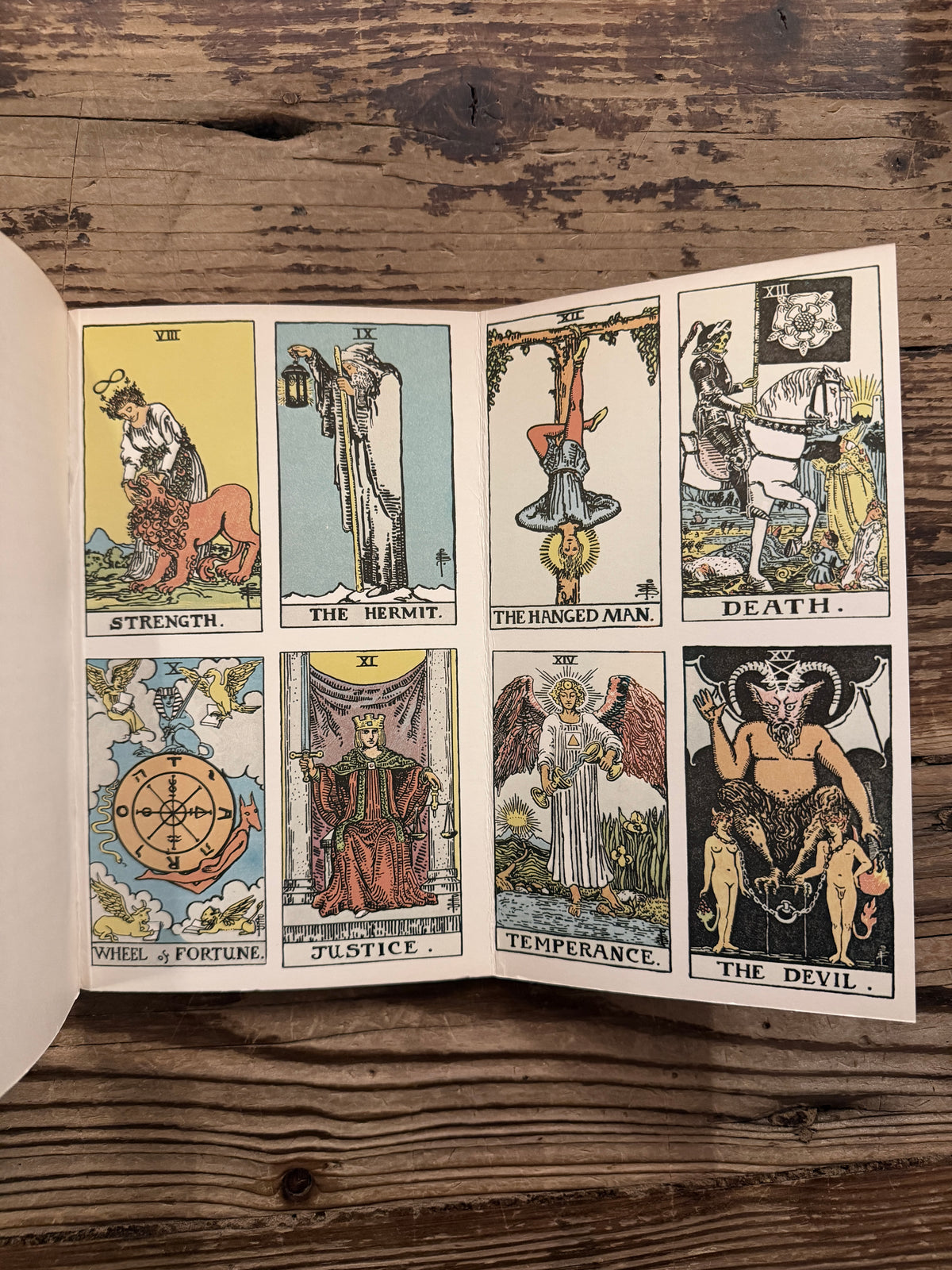 Last page showing the French Flaps with the tarot illustrations by Waite of a book with the title  'The symbolism of the Tarot, philosophy of Occultism in Pictures and Numbers' by P. D. Ouspensky, lying on a wooden surface