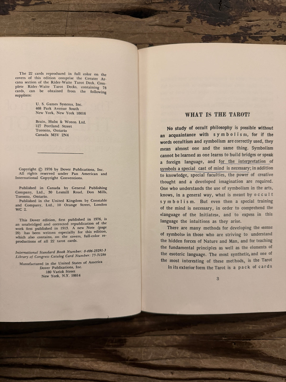 Open book with the title  'The symbolism of the Tarot, philosophy of Occultism in Pictures and Numbers' by P. D. Ouspensky, lying on a wooden surface