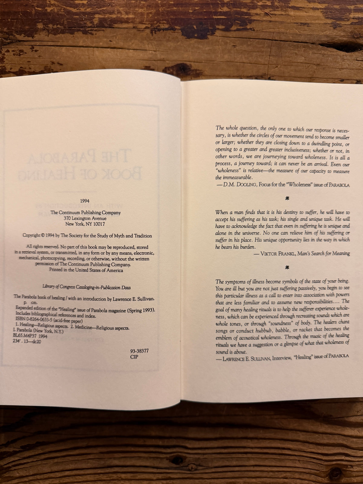 Open book titled 'the Parabola book of healing' on a wooden surface 
