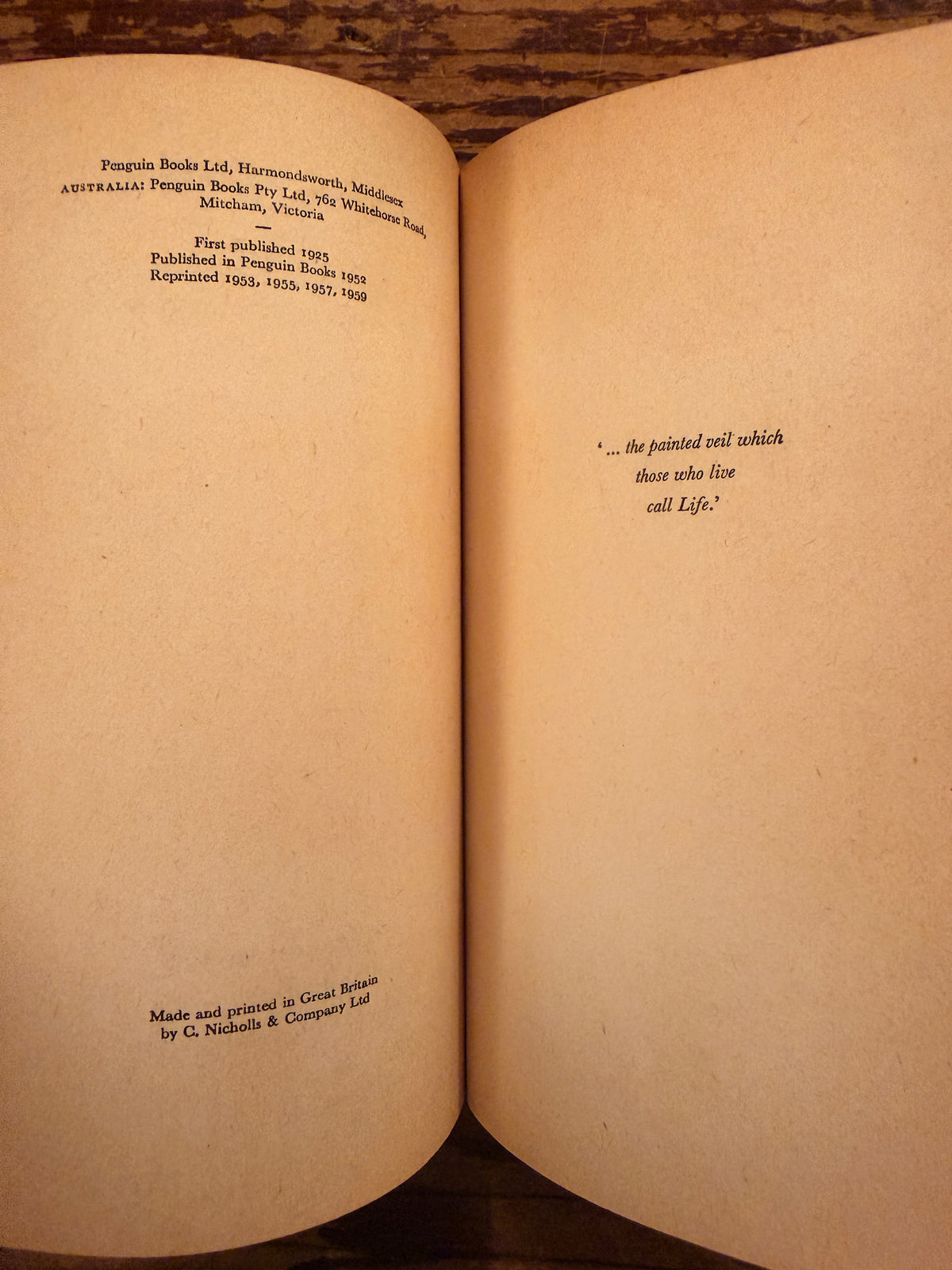 Open book with the title 'The Painted veil' by W. Somerset Maugham, Penguin Books n. 872, reprint 1959, lying on a wooden surface