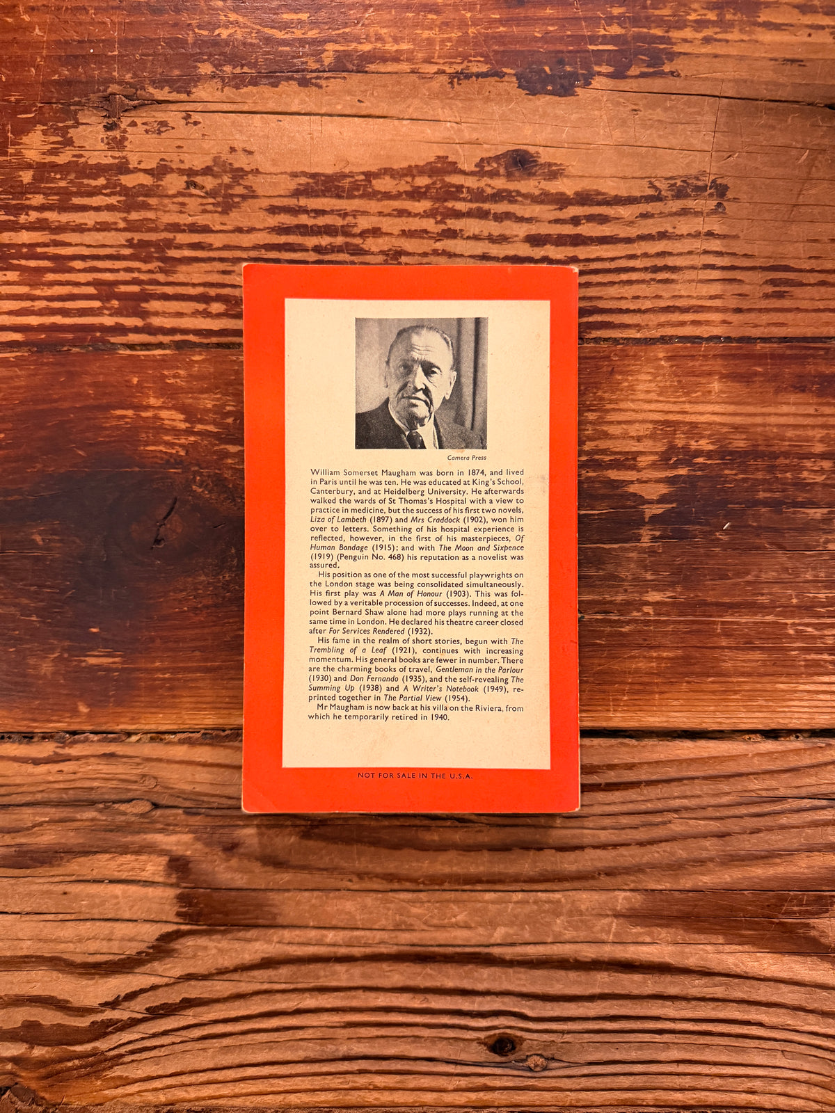 Back cover of a book with the title 'The Painted veil' by W. Somerset Maugham, Penguin Books n. 872, reprint 1959, lying on a wooden surface