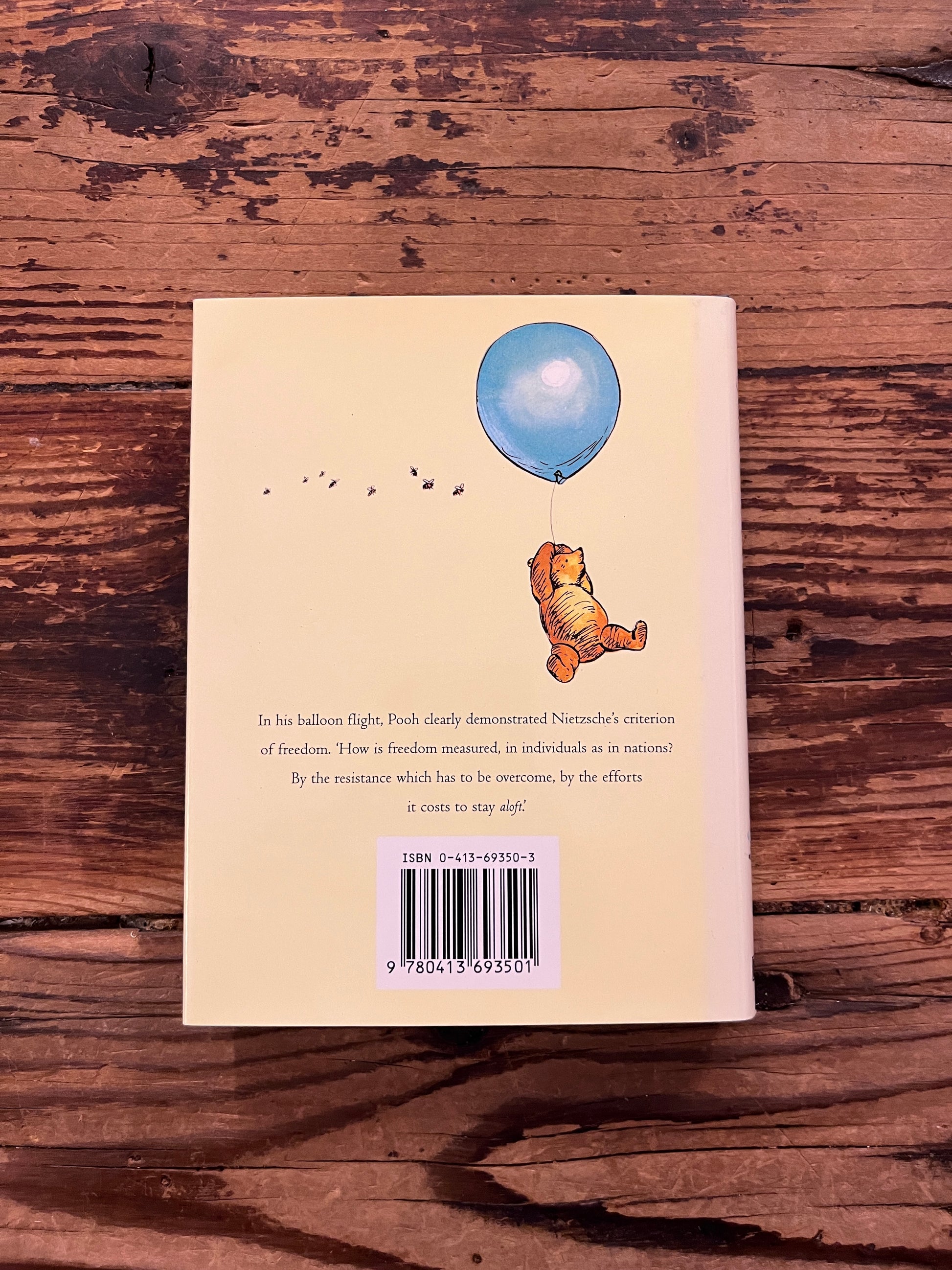 photo of the cover of the book "Pooh and the philosophers" on a wooden background