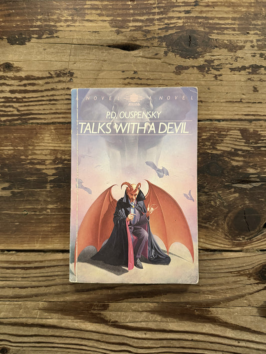 Front cover of a book with the title 'Talks with a Devil' by P.D. Ouspensky, lying on a wooden surface