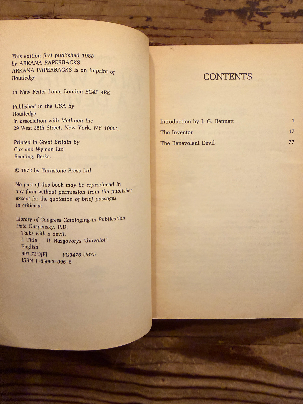 Open book with the title 'Talks with a Devil' by P.D. Ouspensky, lying on a wooden surface