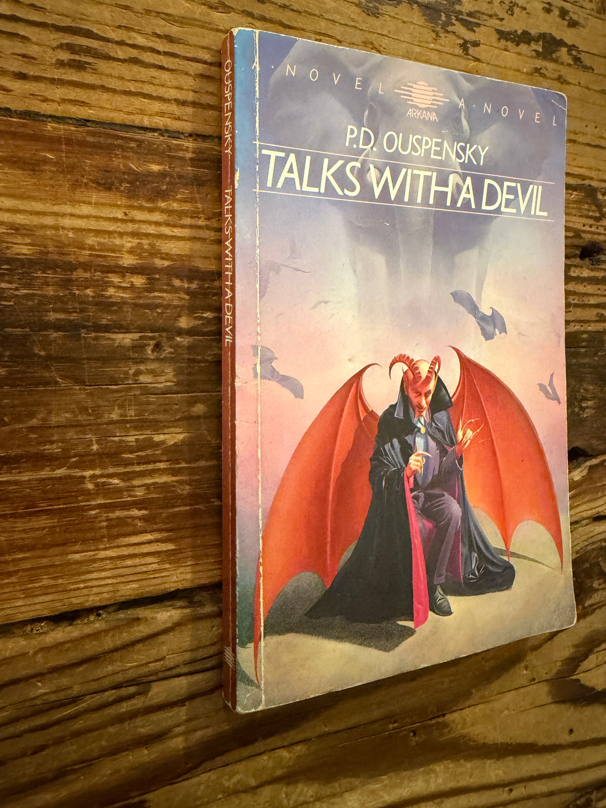 Front cover and spine of a book with the title 'Talks with a Devil' by P.D. Ouspensky, lying on a wooden surface