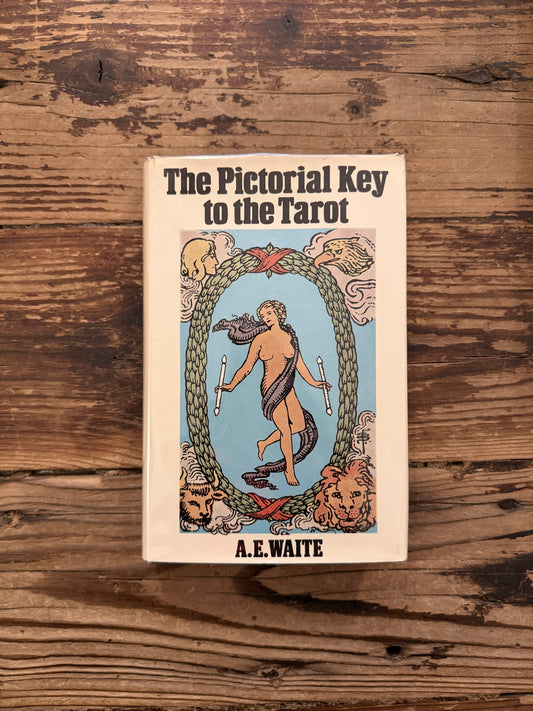 Front cover of a book titled 'The Pictorial Key to the Tarot' by A.E. on a wooden surface 
