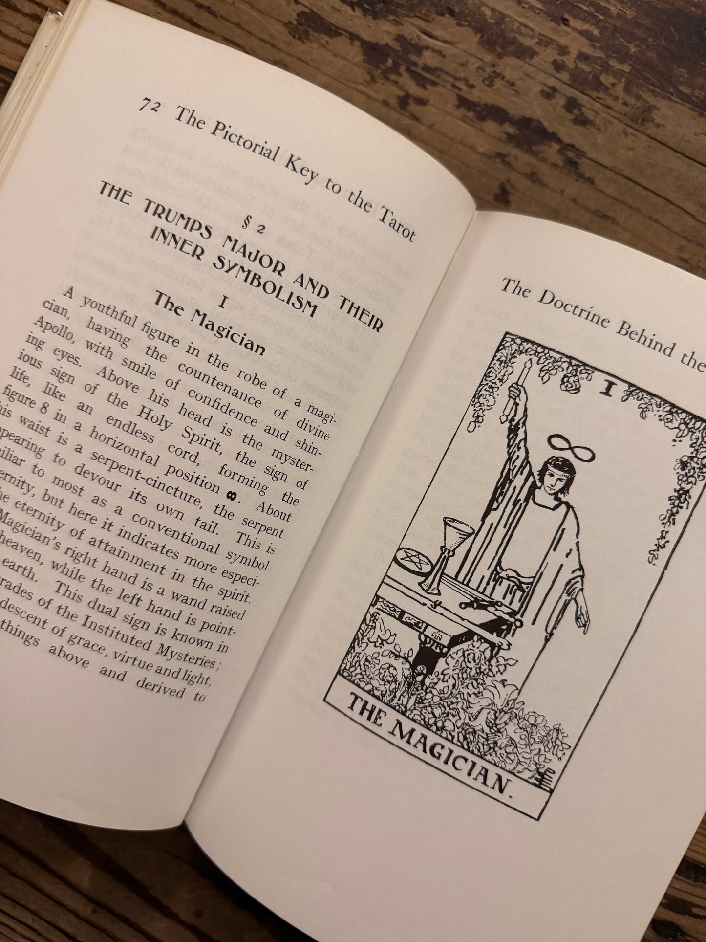 Open book titled 'The Pictorial Key to the Tarot' by A.E. on a wooden surface 
