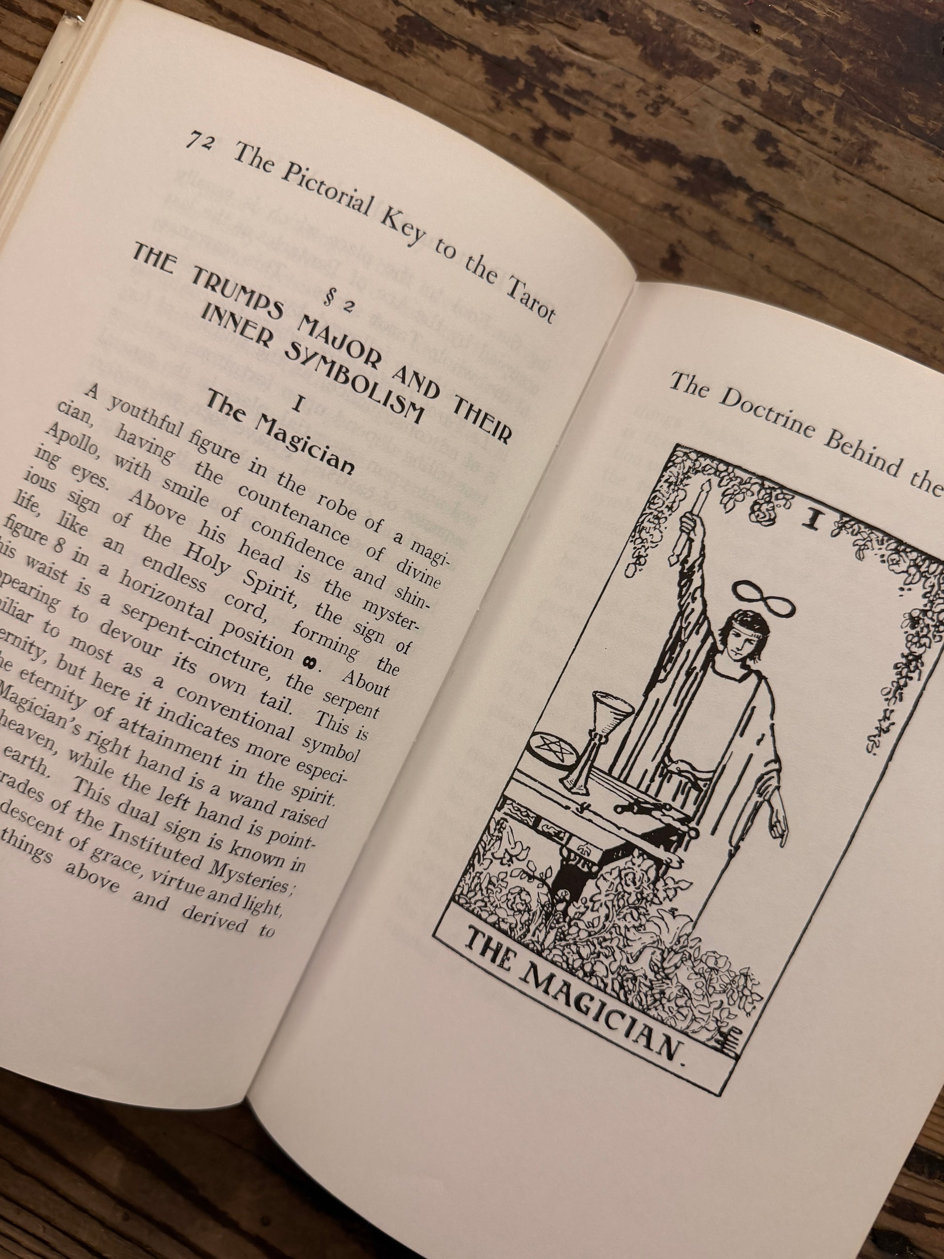 Open book titled 'The Pictorial Key to the Tarot' by A.E. on a wooden surface 