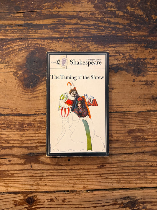 photo of the cover of the book "The taming of the shrew" on a wooden background