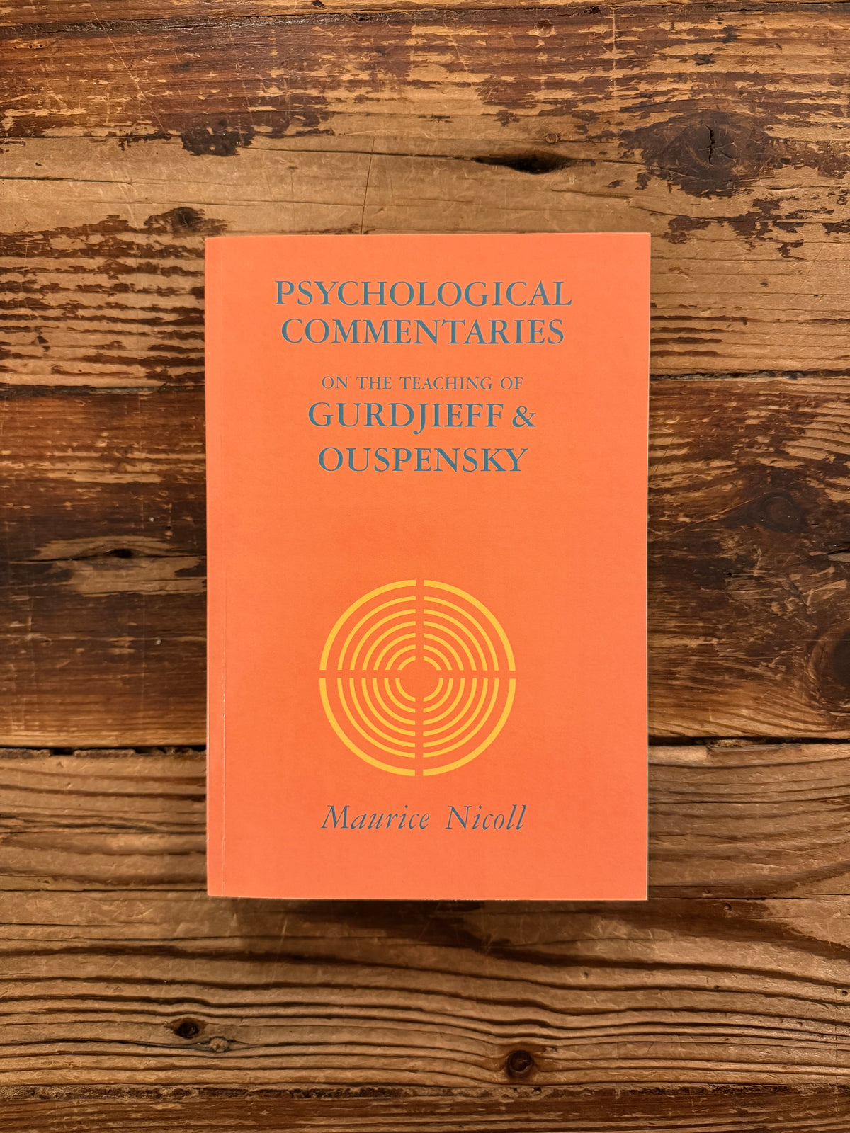 Front cover of a book titled 'Psychological commentaries on the teaching of Gurdjieff & Ouspensky, vol I' by Maurice Nicoll lying on wooden surface