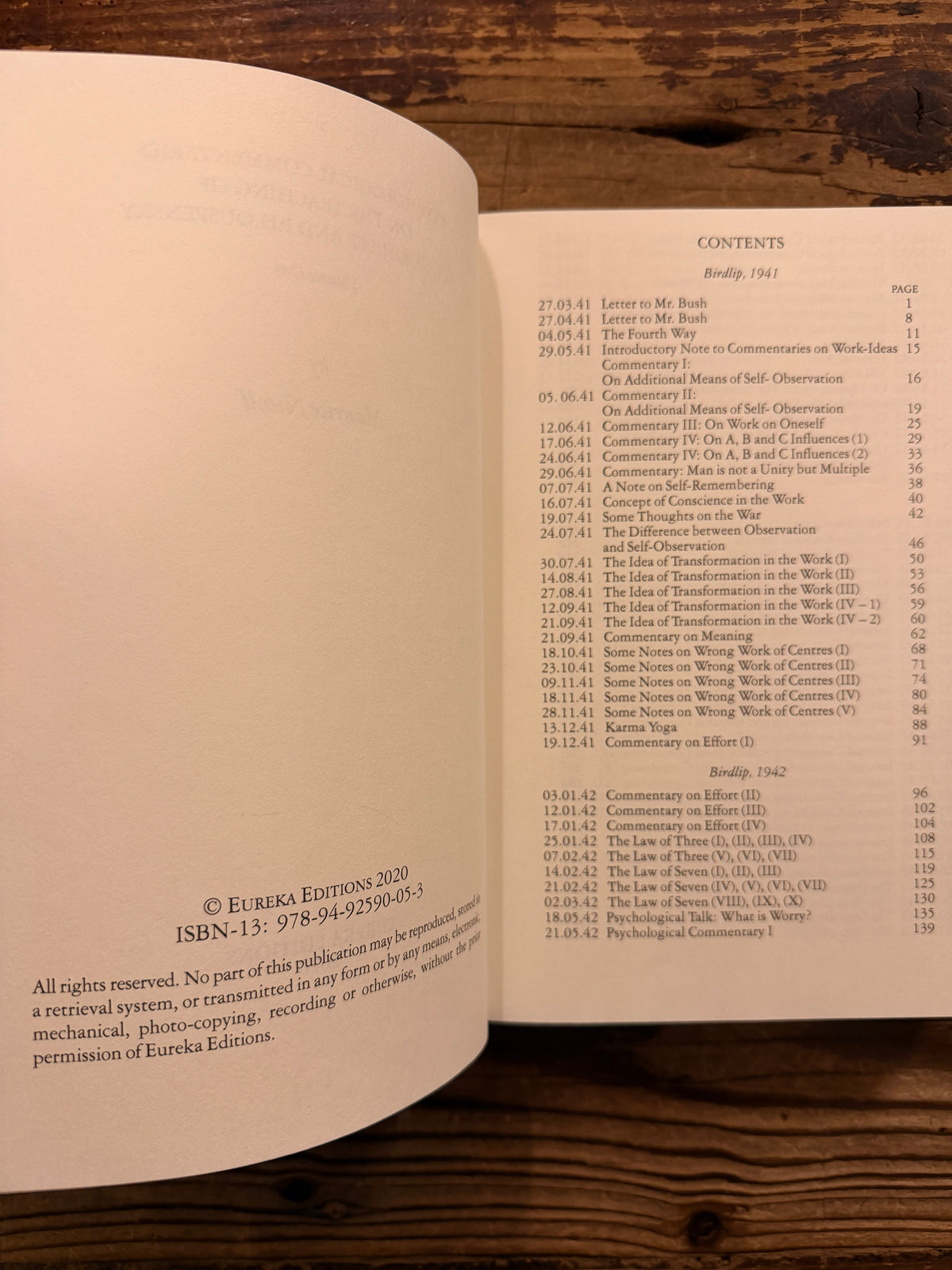 Open book titled 'Psychological commentaries on the teaching of Gurdjieff & Ouspensky, vol I' by Maurice Nicoll lying on wooden surface