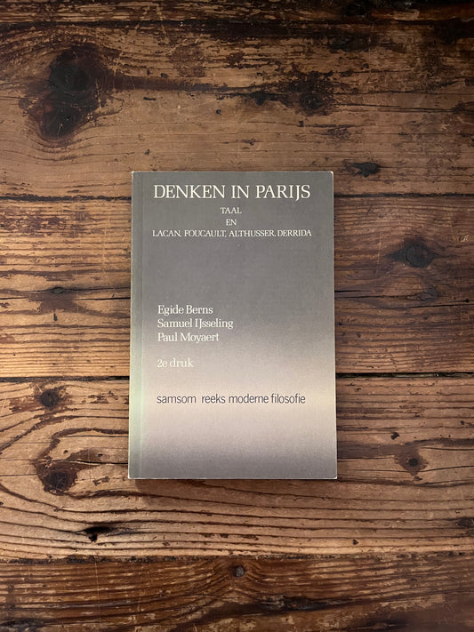 photo of the cover of the book " denken in parijs " on wooden background