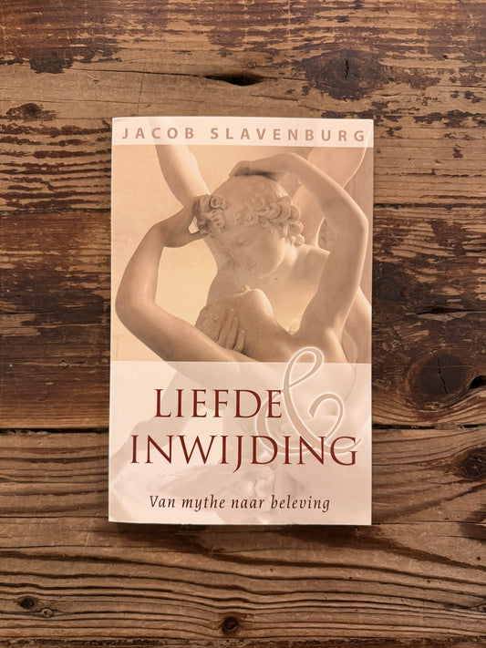 Voorkant van boek met de titel 'liefde & inwijding, van mythe naar beleving' door Jacob Slavenburg op een houten achtergrond 