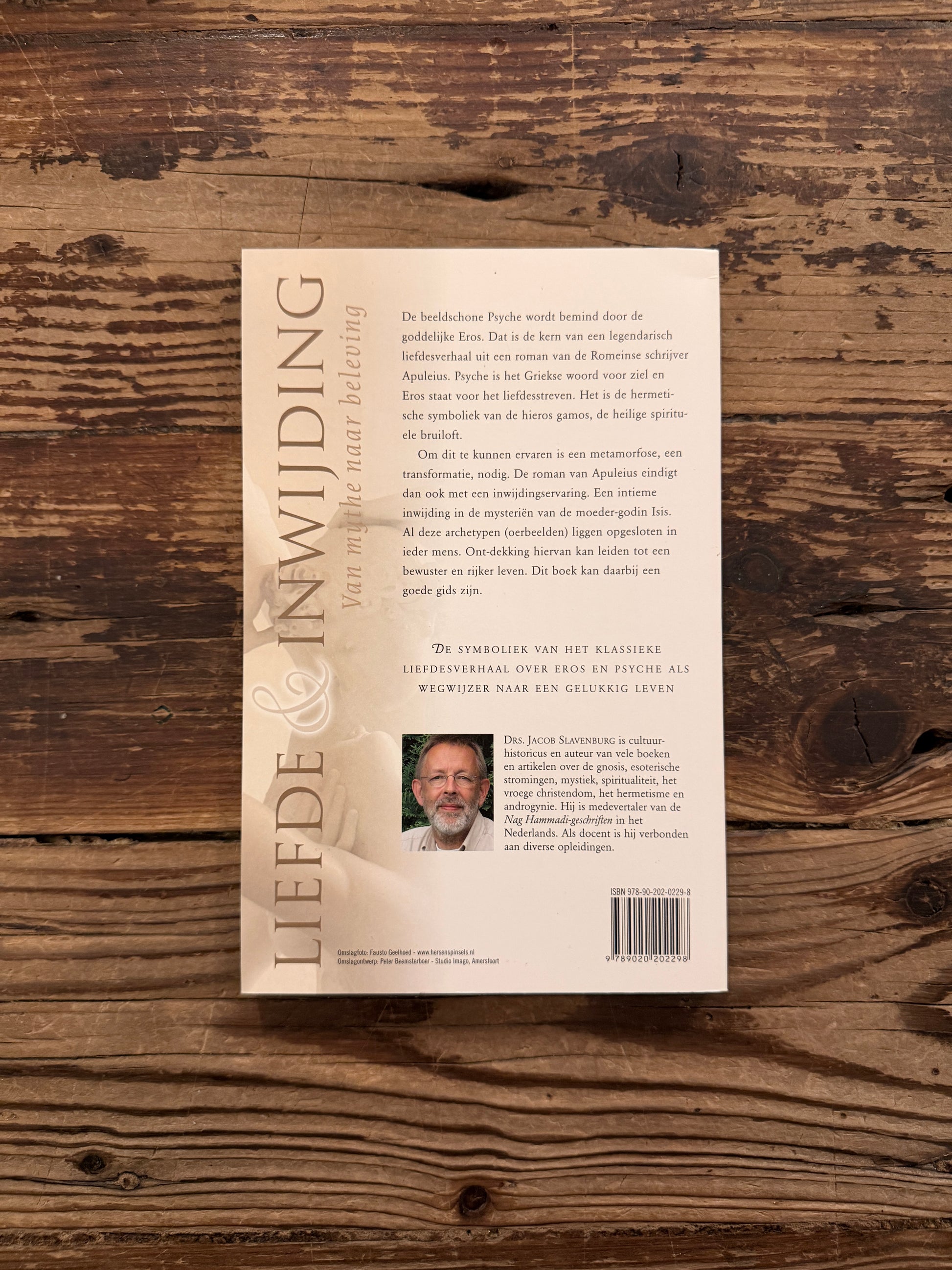 Achterkant van boek met de titel 'liefde & inwijding, van mythe naar beleving' door Jacob Slavenburg op een houten achtergrond 