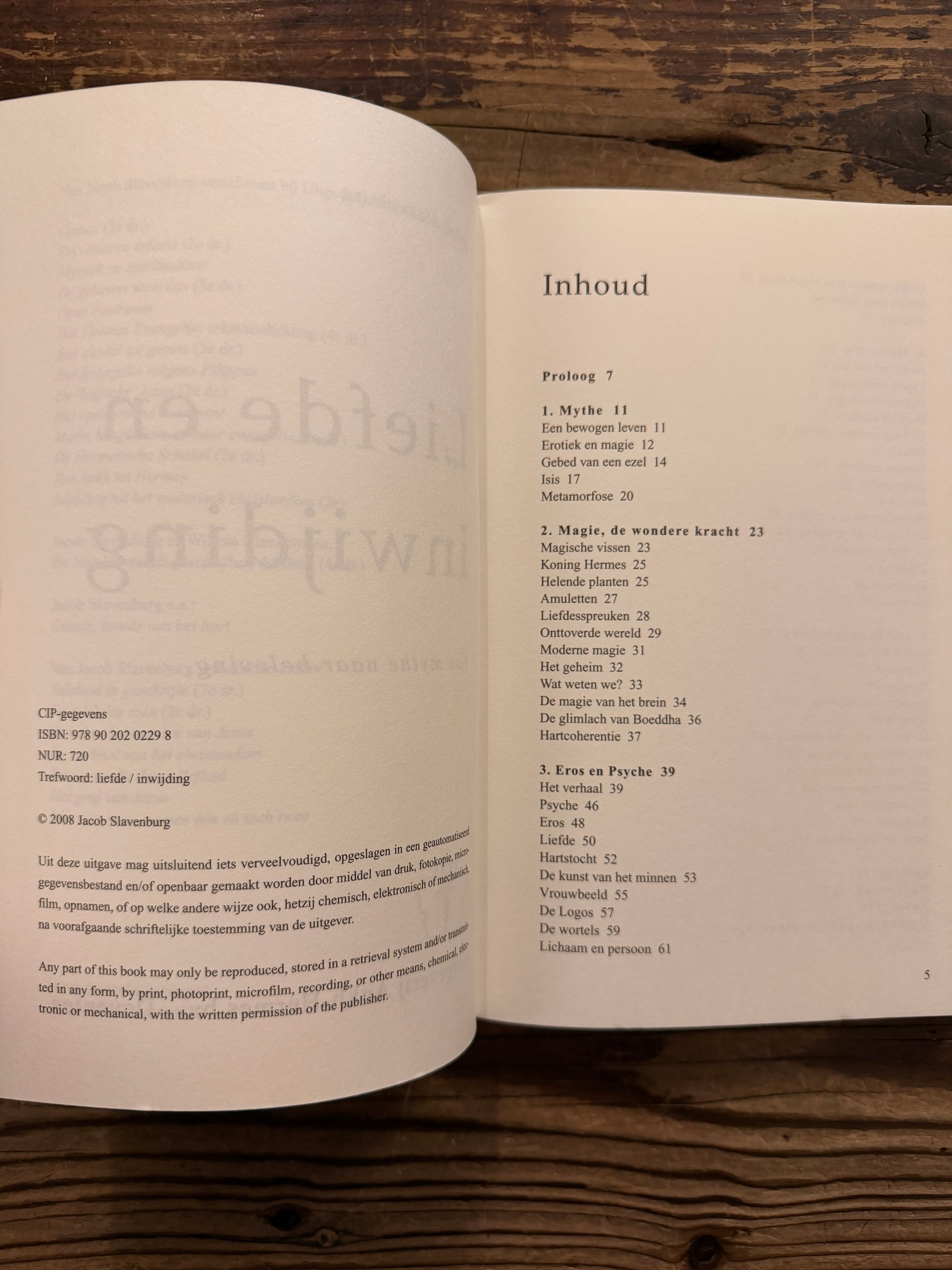 Open boek met de titel 'liefde & inwijding, van mythe naar beleving' door Jacob Slavenburg op een houten achtergrond 