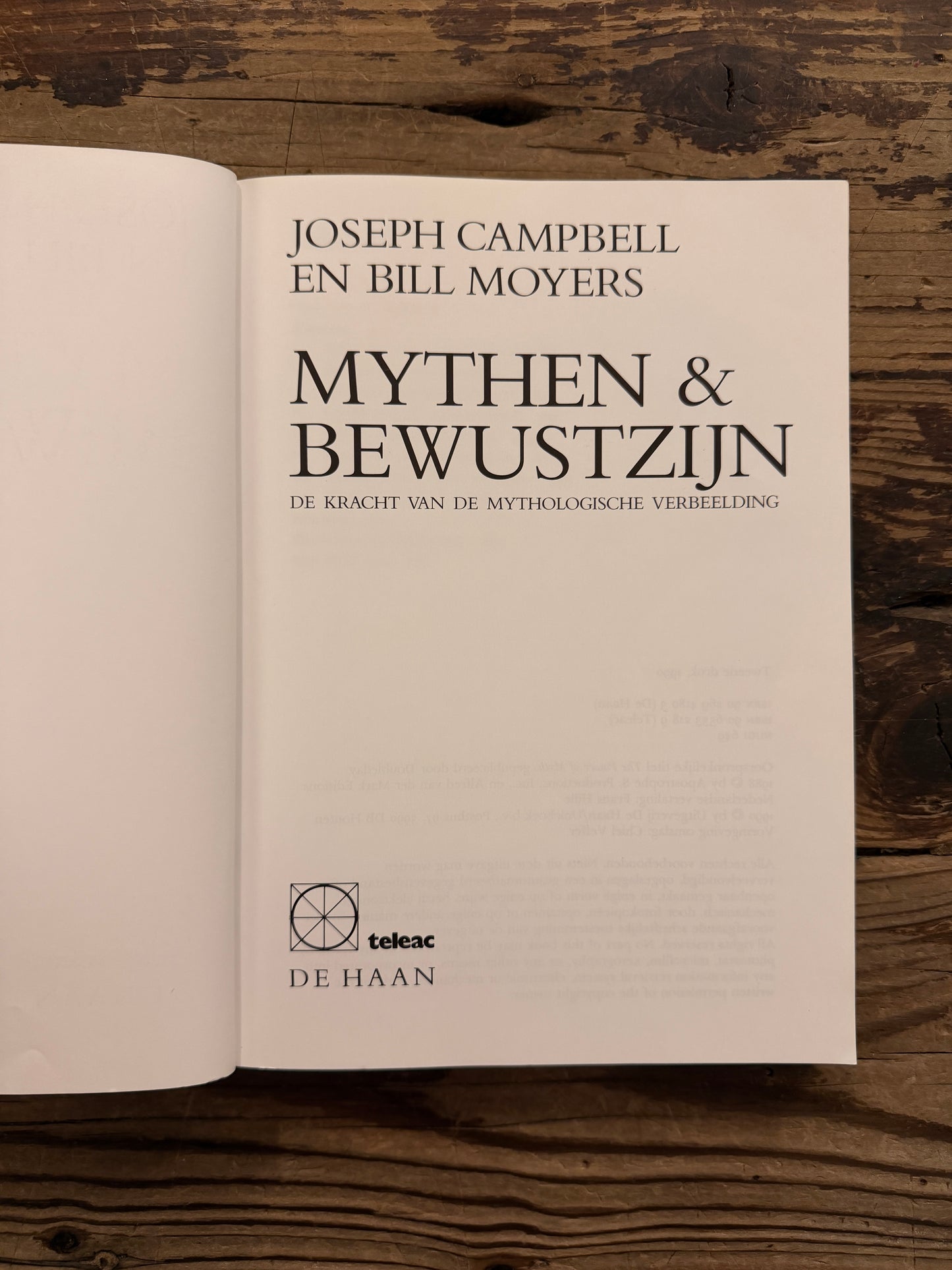 Open boek met de titel 'mythen & bewustzijn' door Joseph Campbell en Bill Moyers op een houten achtergrond 