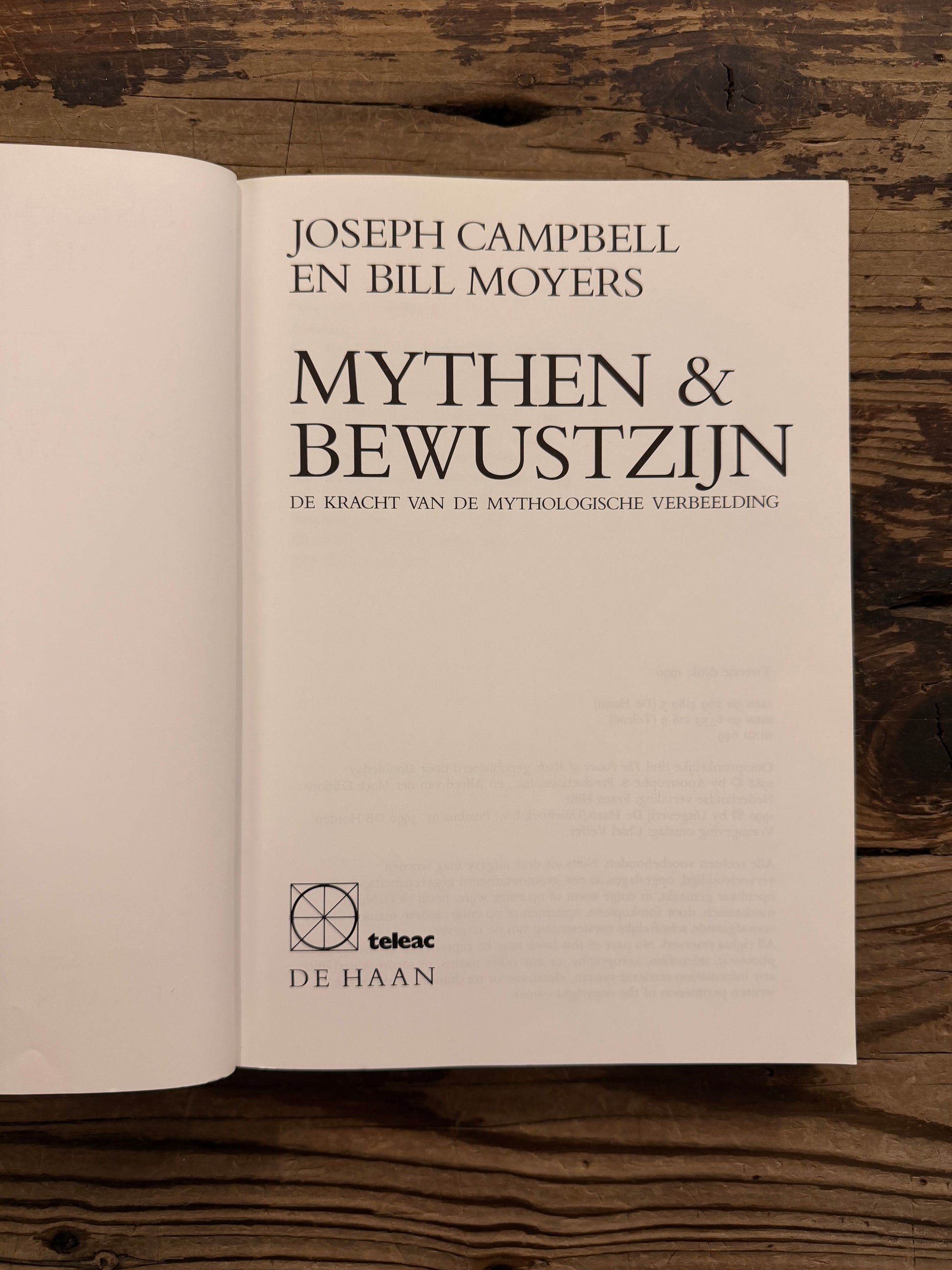 Open boek met de titel 'mythen & bewustzijn' door Joseph Campbell en Bill Moyers op een houten achtergrond 