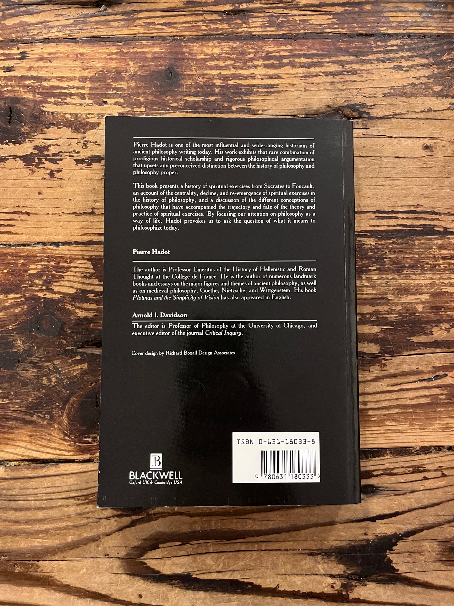 photo of the cover of the book "philosophy as a way of life" on a wooden background