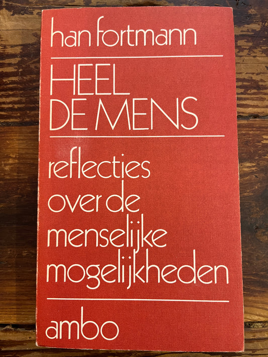 Voorkant van boek met de titel 'heel de mens, reflecties over de menselijke mogelijkheden' door Han Fortmann op een houten achtergrond 
