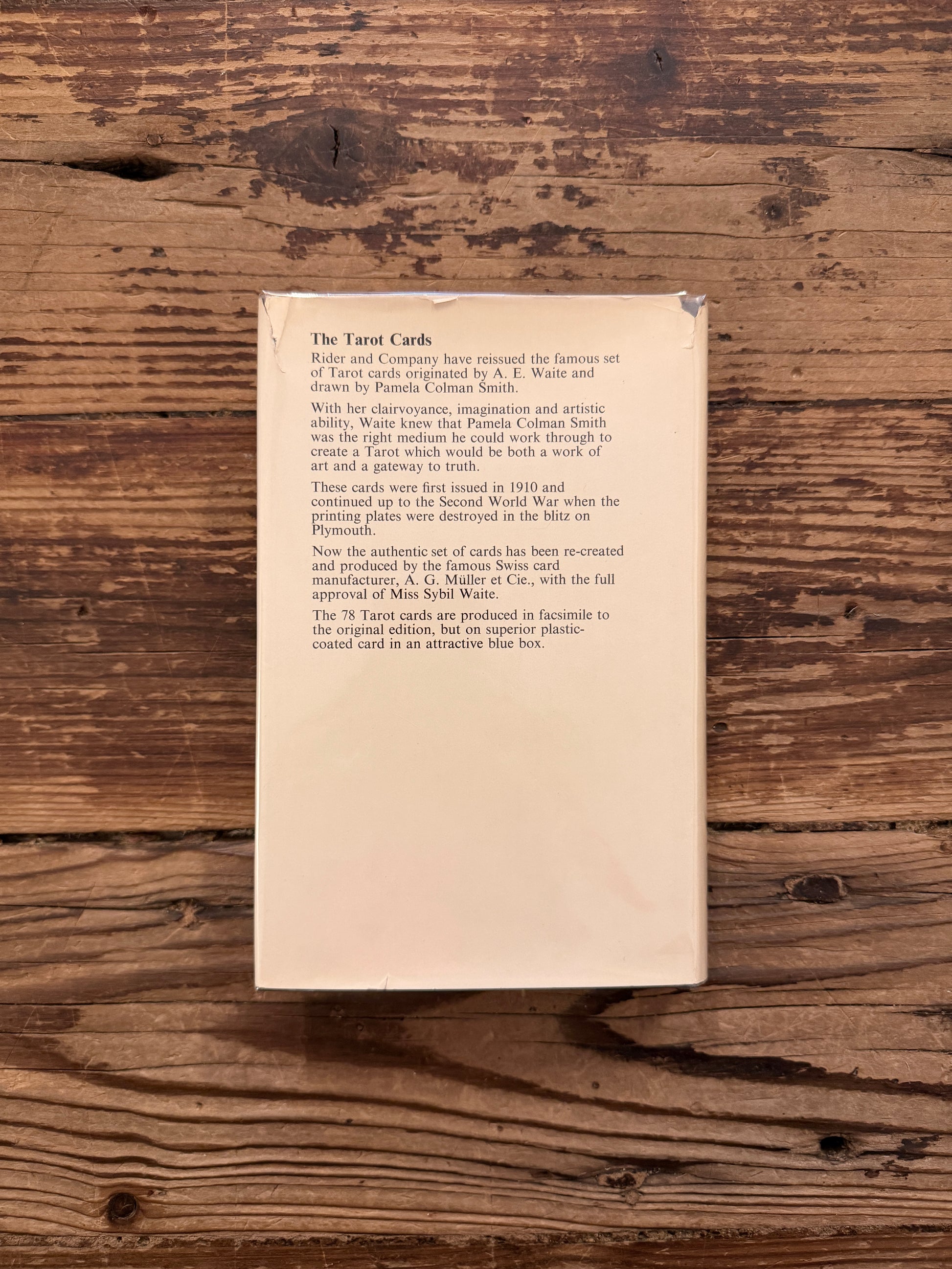 Back cover of a book titled 'The Pictorial Key to the Tarot' by A.E. on a wooden surface 